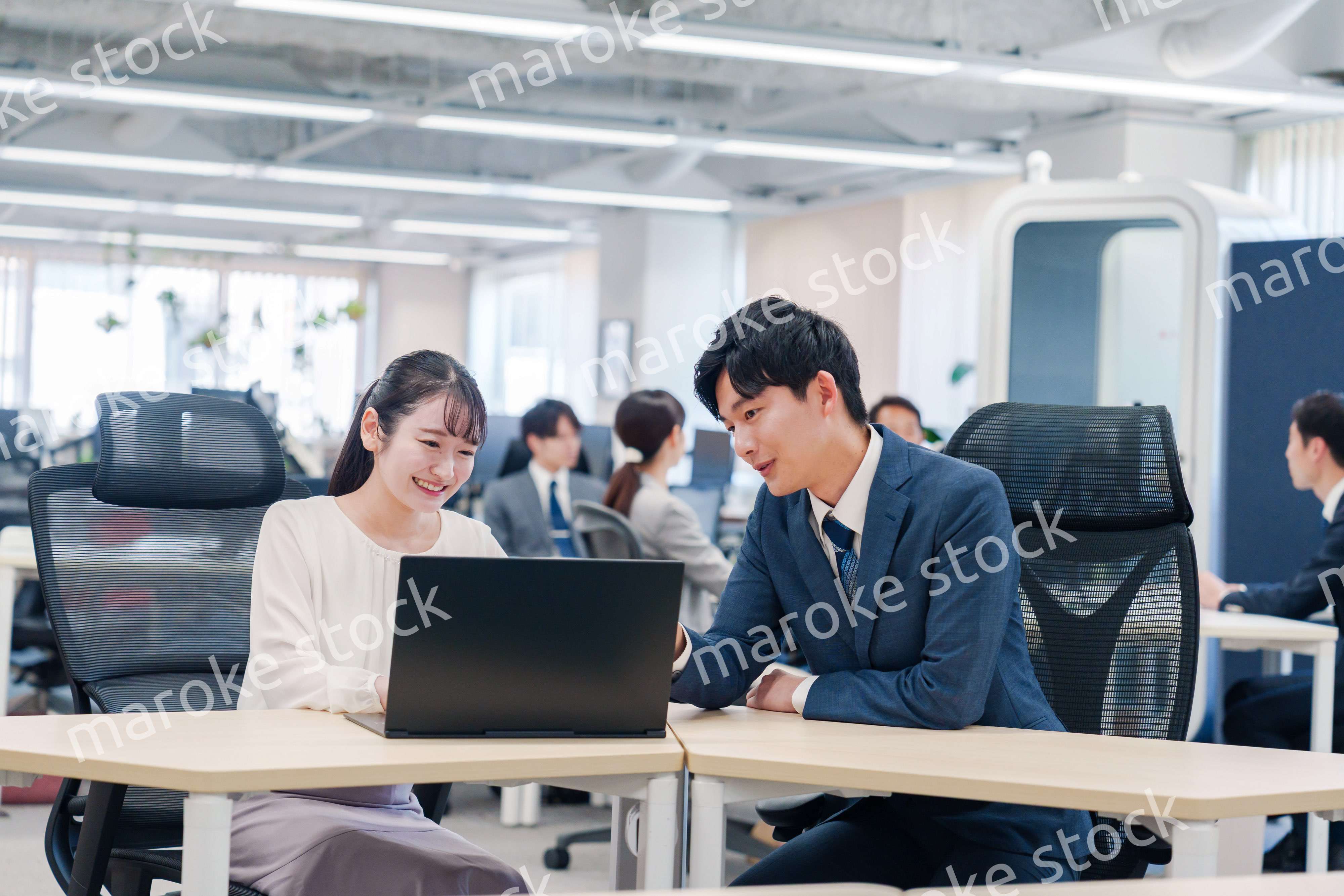 先輩社員から業務を教えてもらう新人の女性