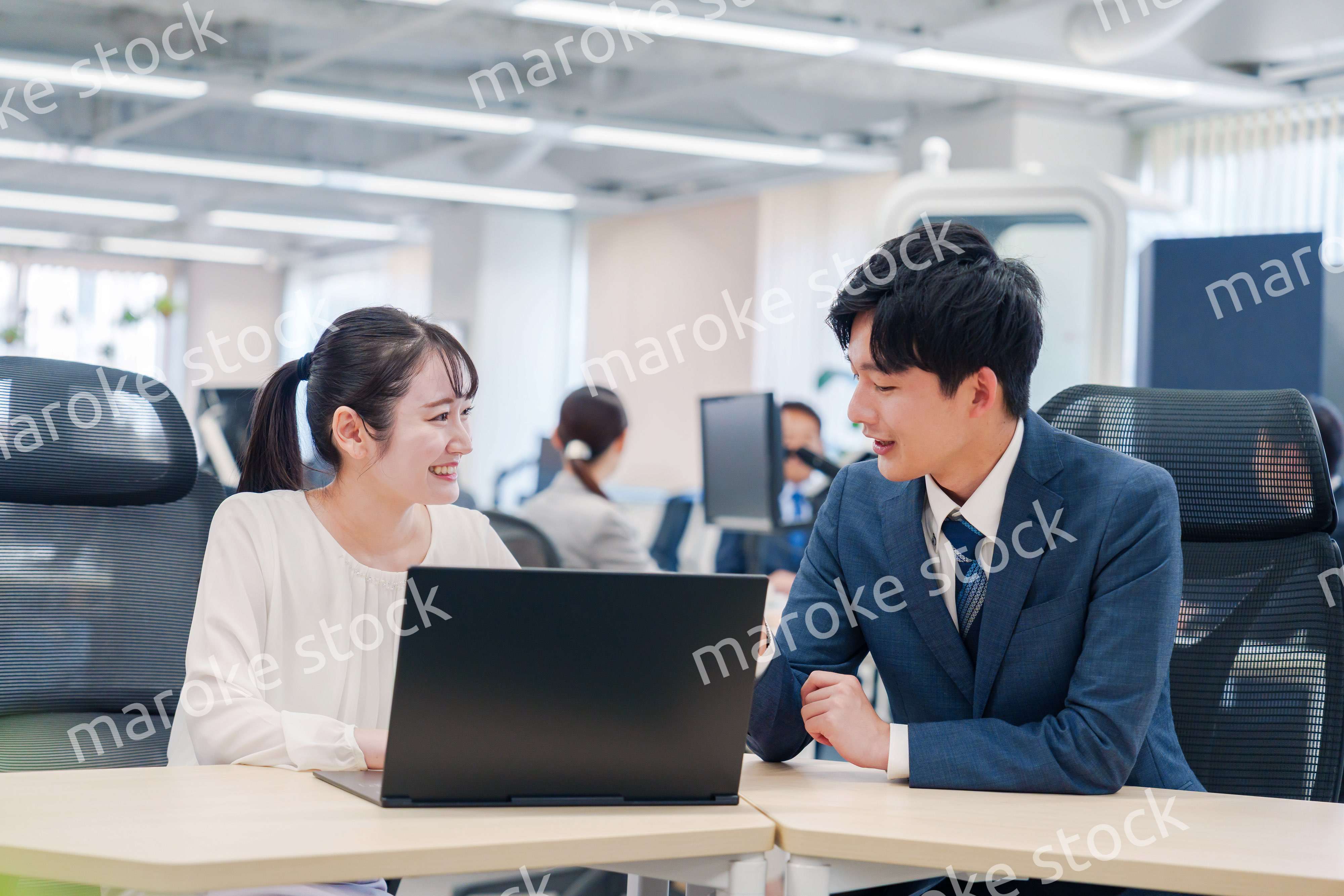 先輩社員から業務を教えてもらう新人の女性