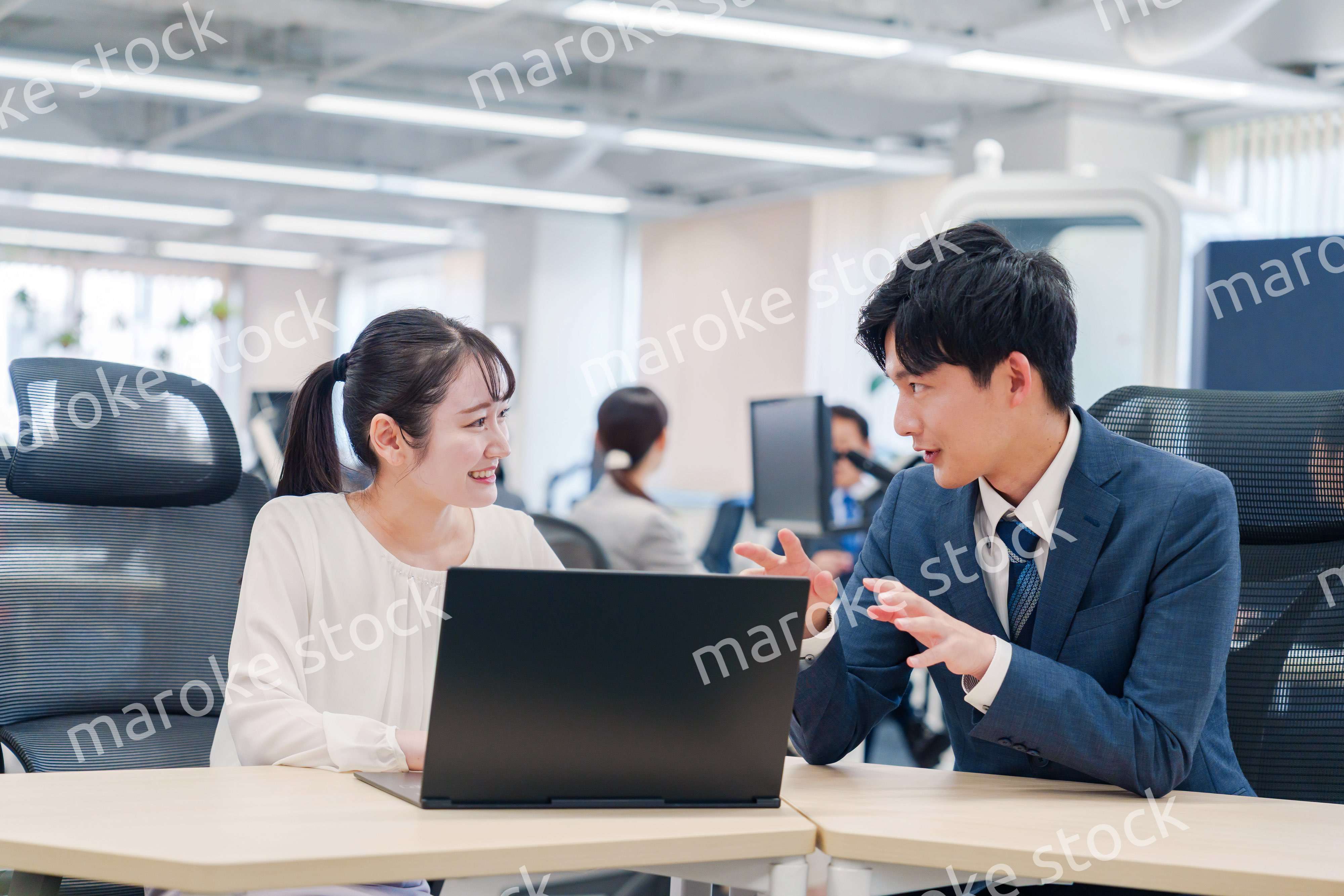 先輩社員から業務を教えてもらう新人の女性