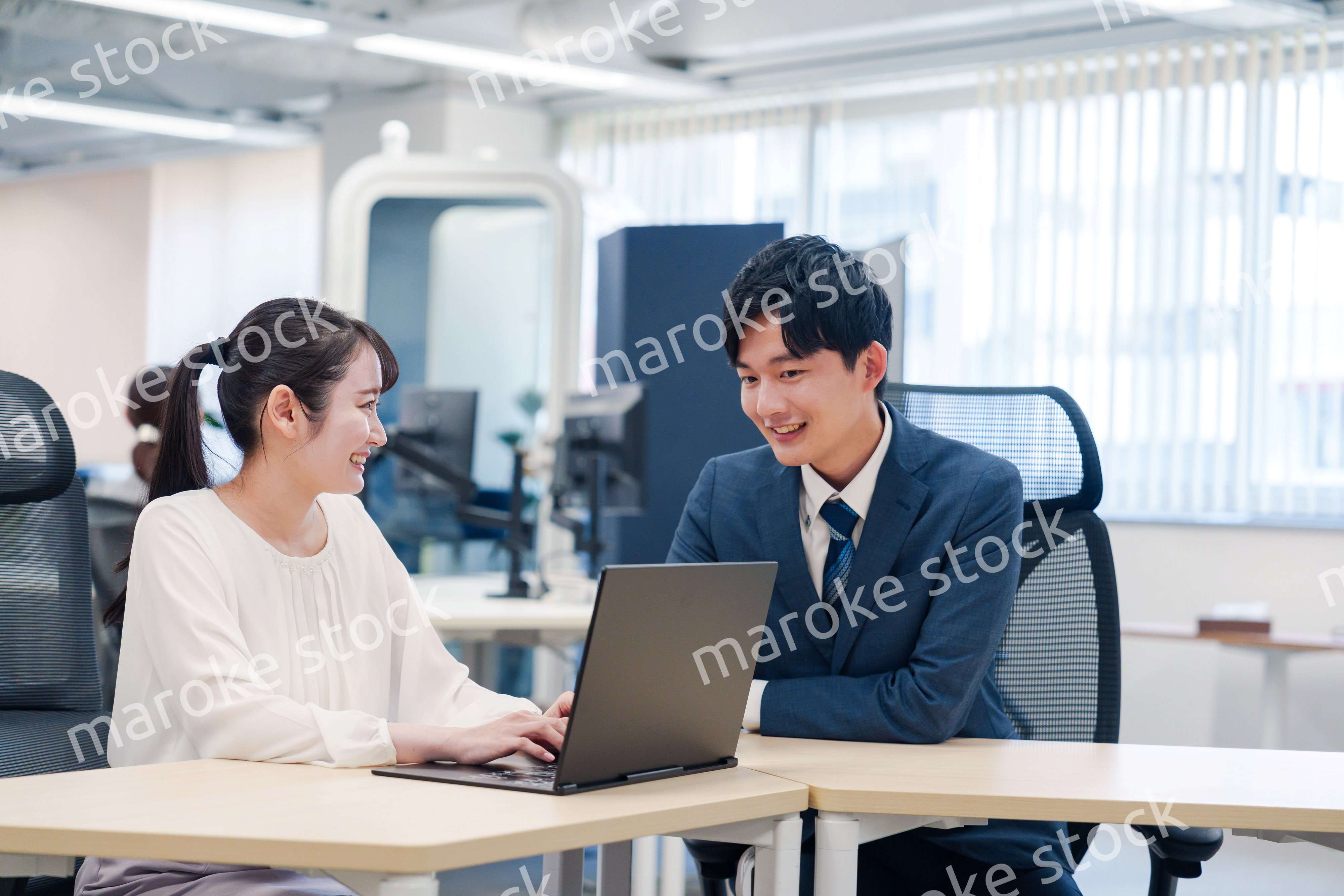 先輩社員から業務を教えてもらう新人の女性