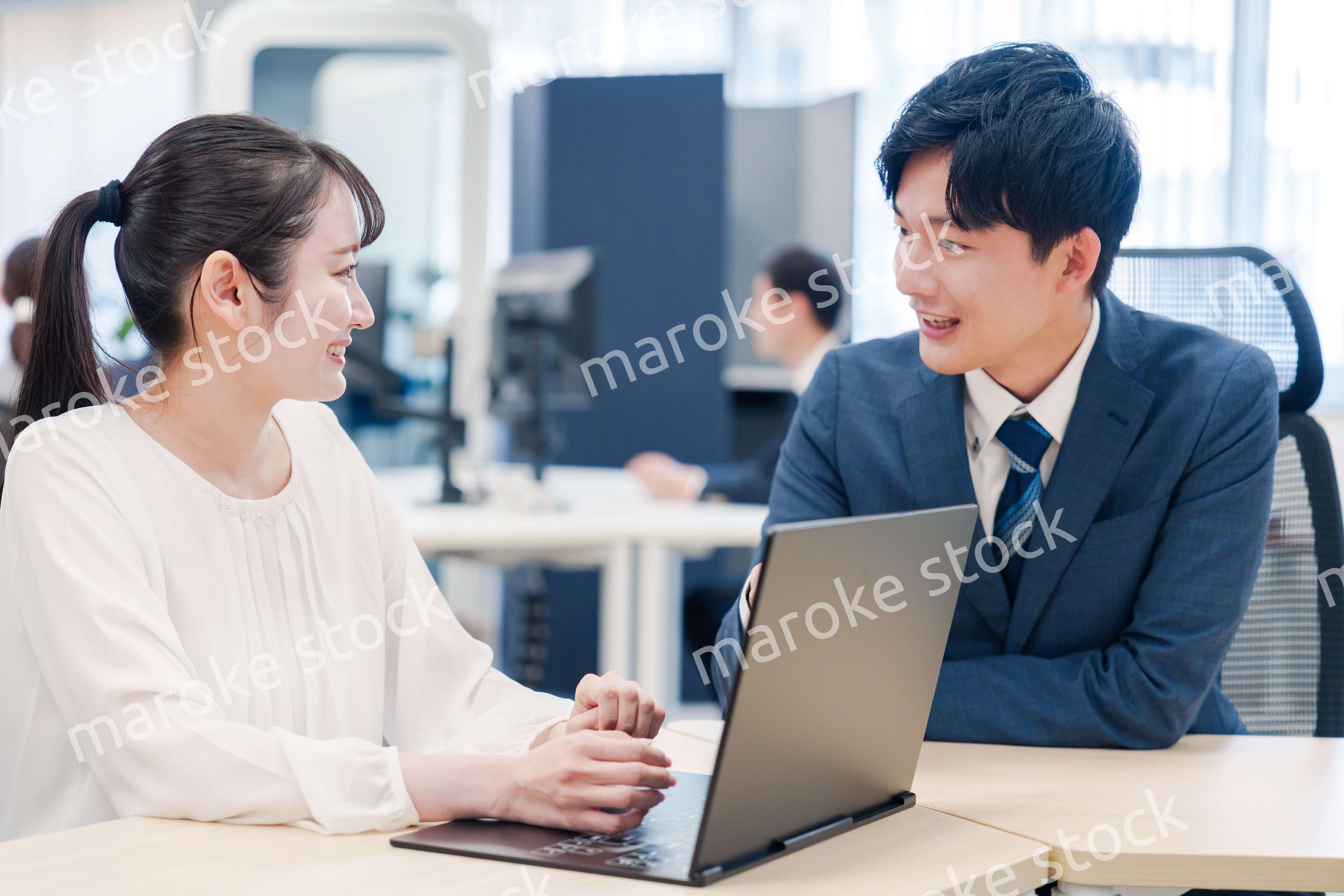 先輩社員から業務を教えてもらう新人の女性