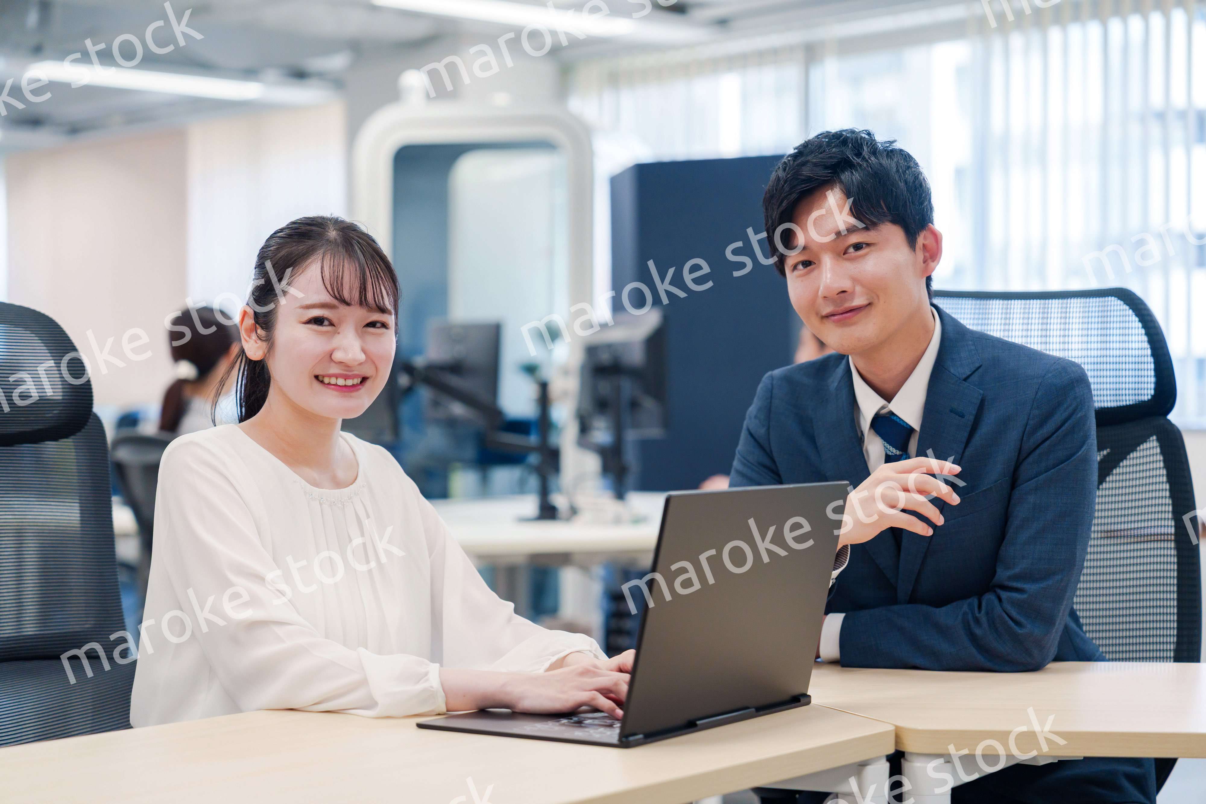 先輩社員から業務を教えてもらう新人の女性