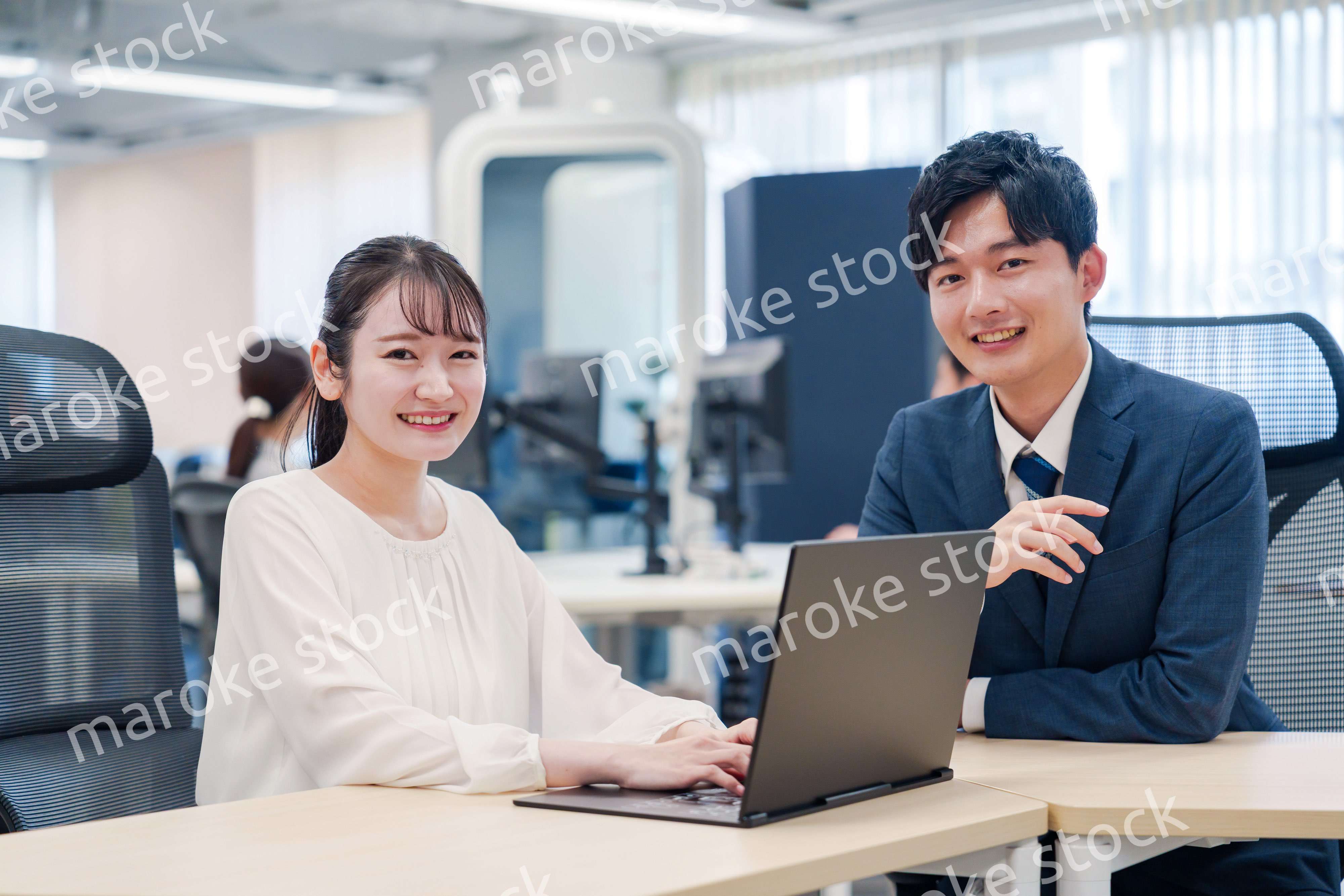 先輩社員から業務を教えてもらう新人の女性