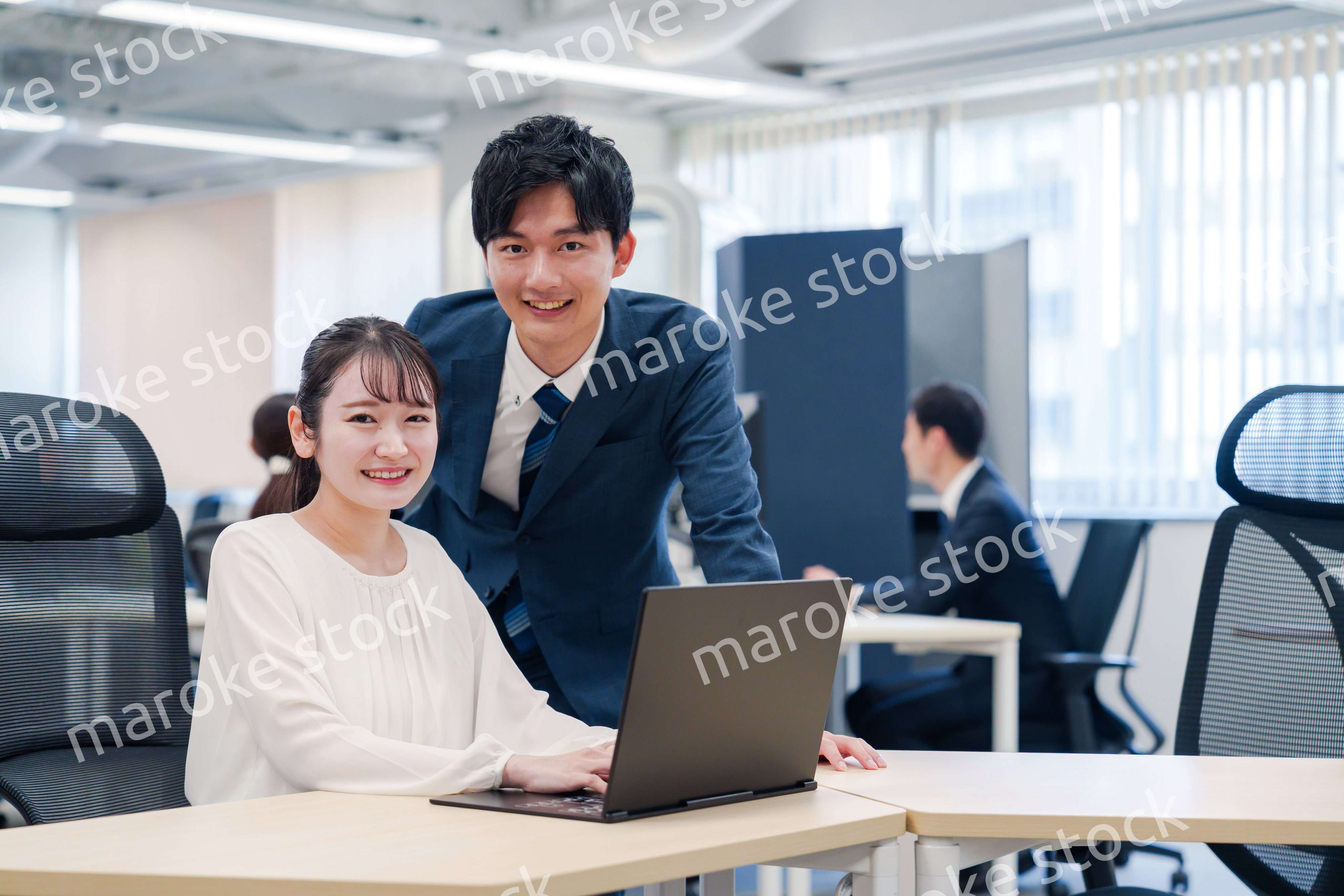 先輩社員から業務を教えてもらう新人の女性