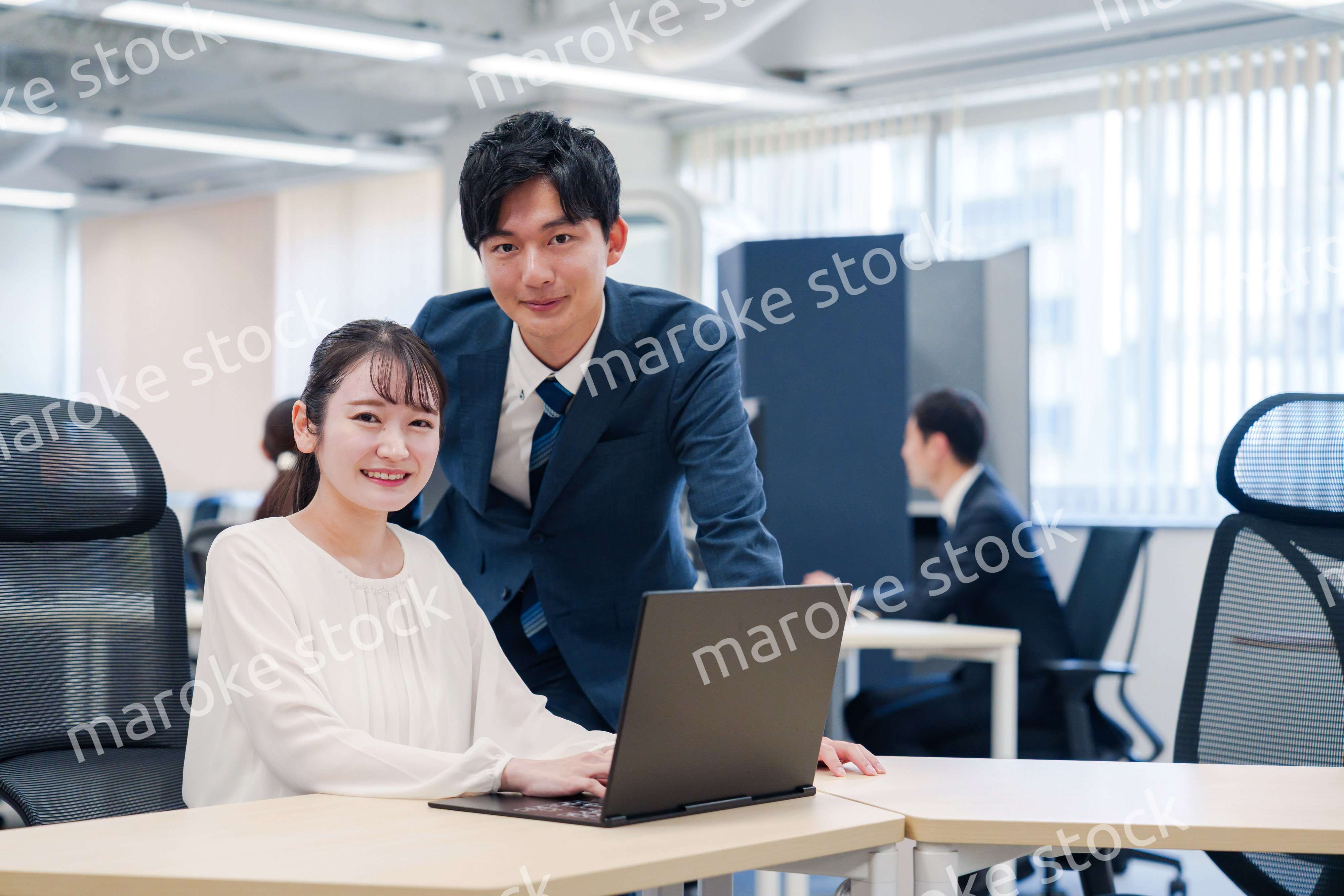 先輩社員から業務を教えてもらう新人の女性