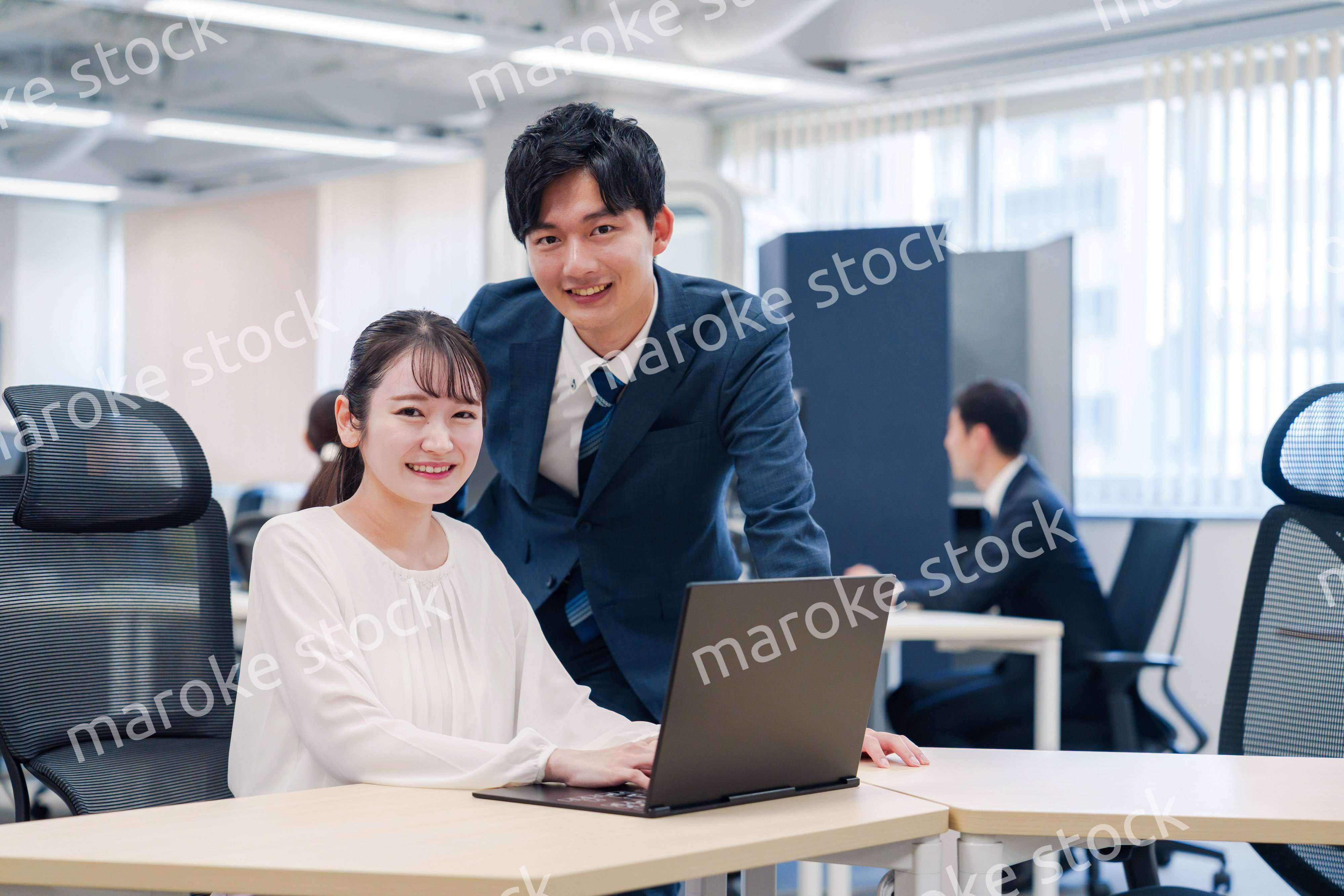 先輩社員から業務を教えてもらう新人の女性