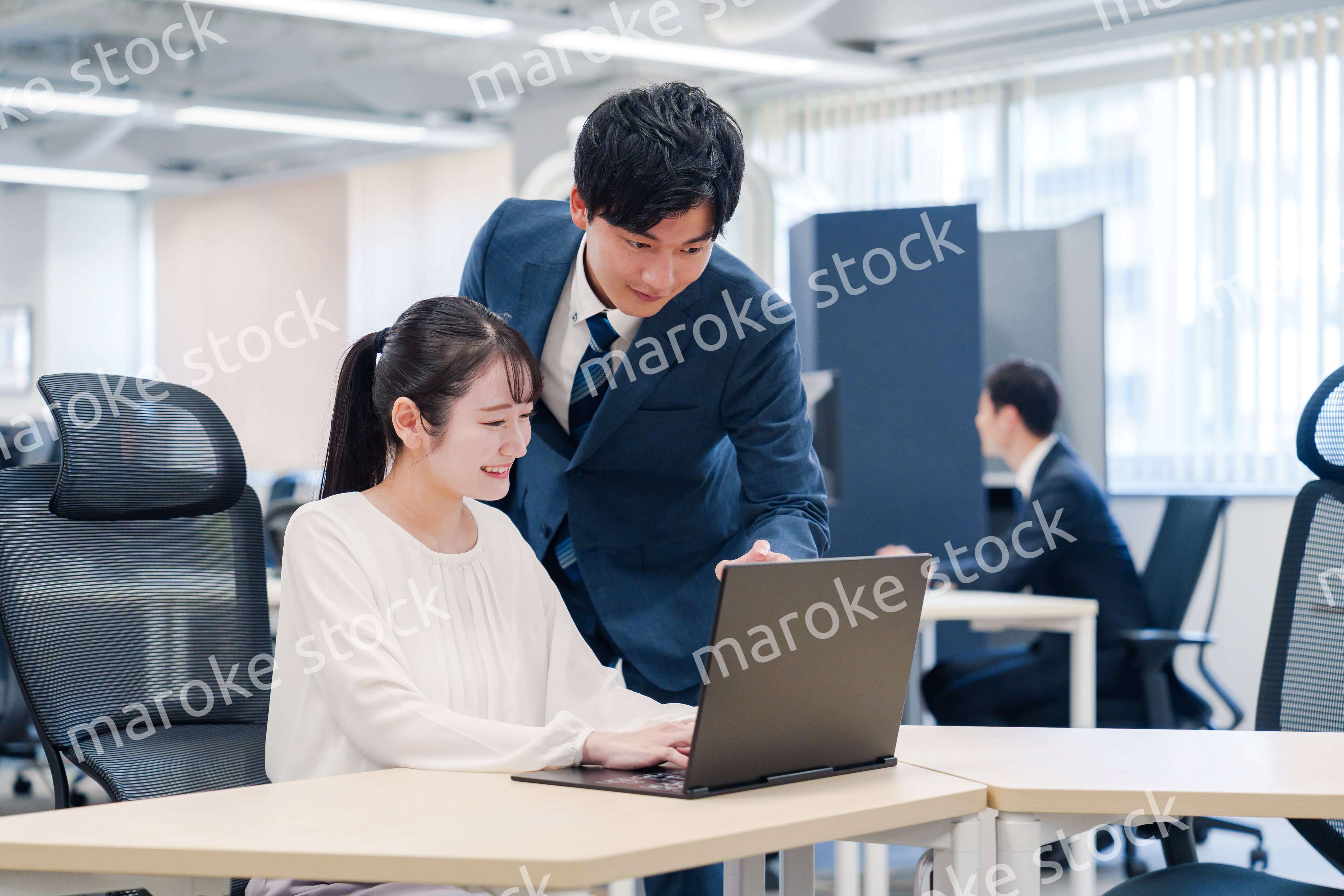 先輩社員から業務を教えてもらう新人の女性