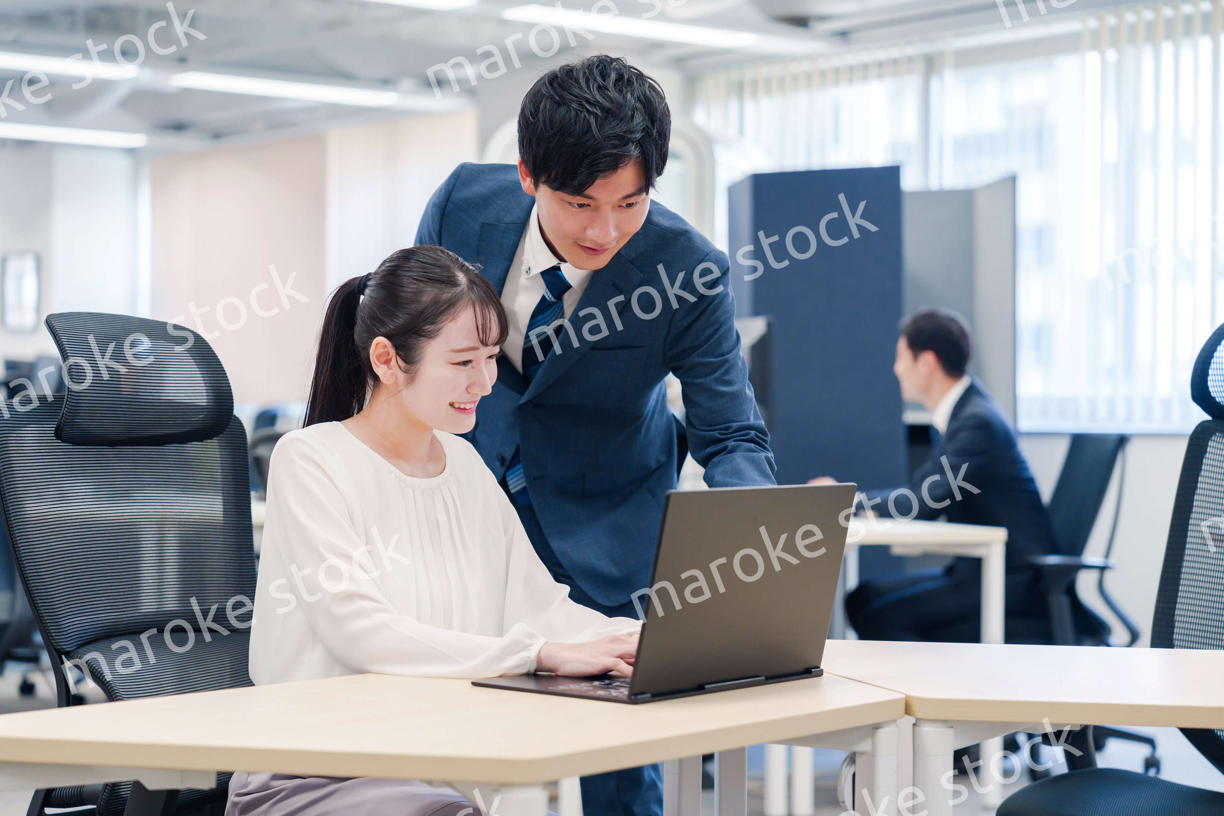 先輩社員から業務を教えてもらう新人の女性