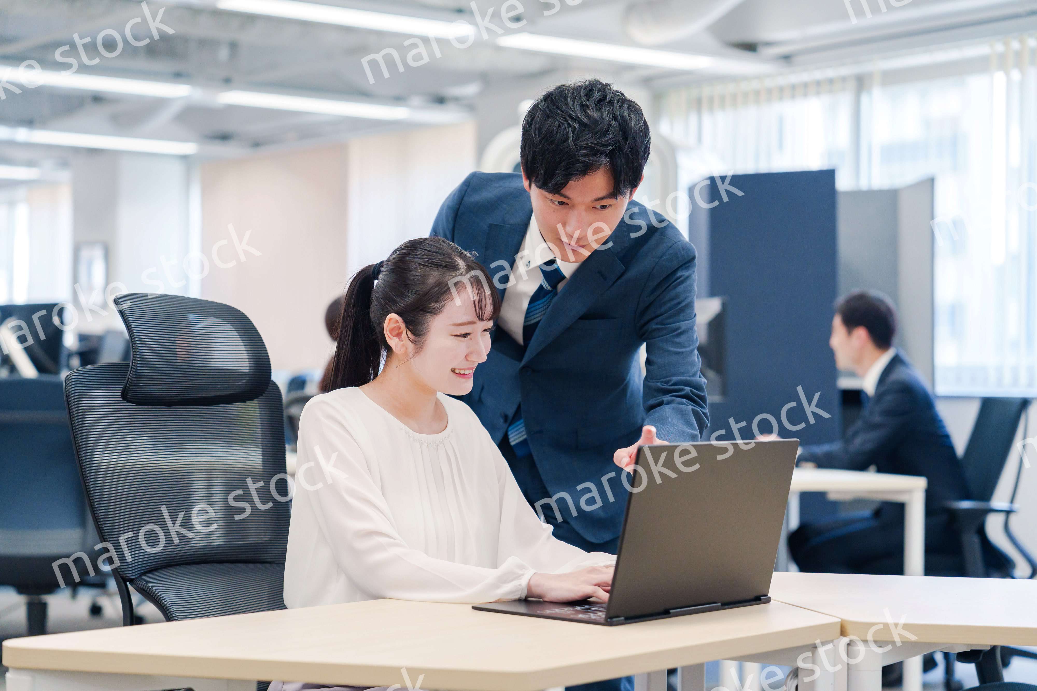 先輩社員から業務を教えてもらう新人の女性