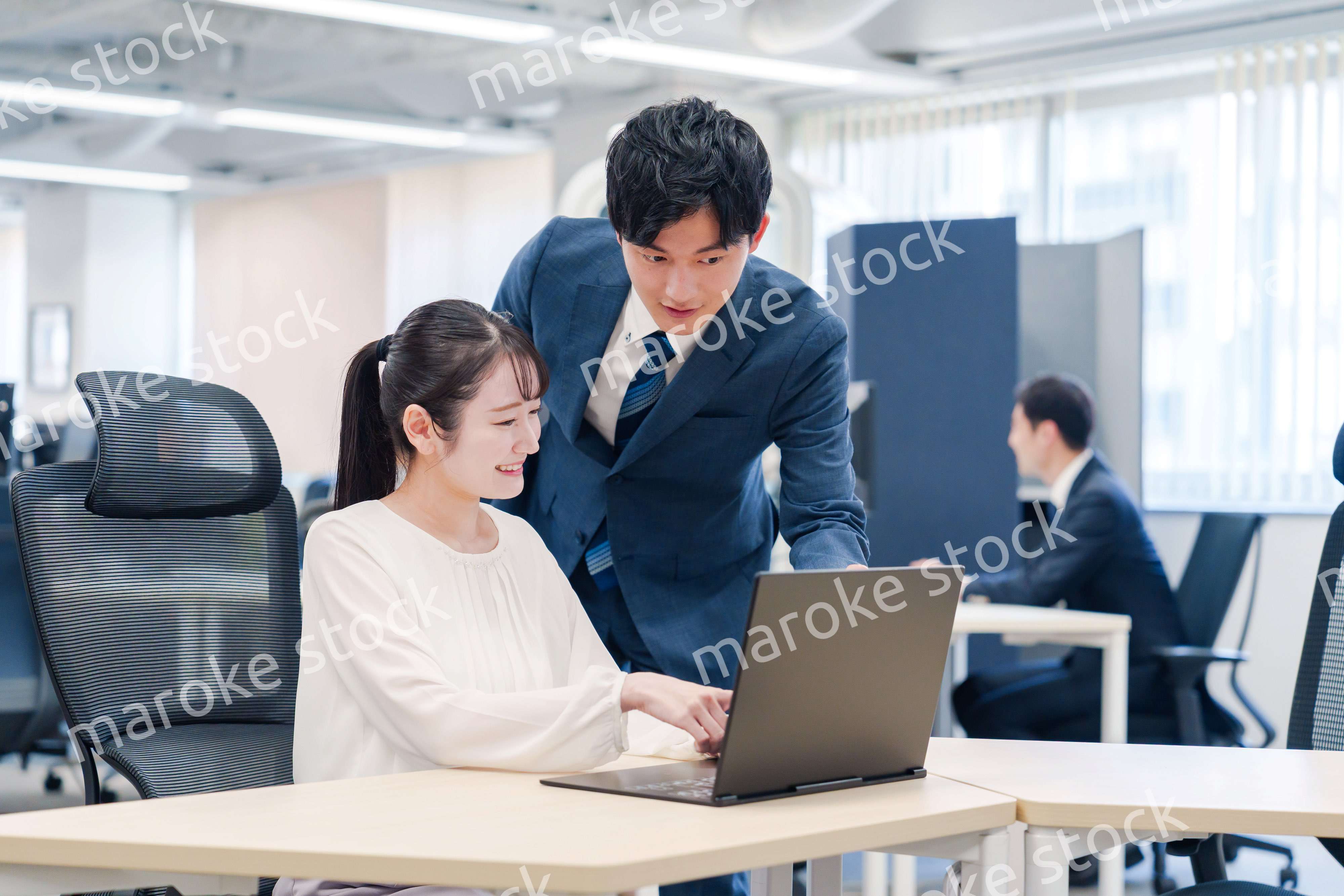 先輩社員から業務を教えてもらう新人の女性