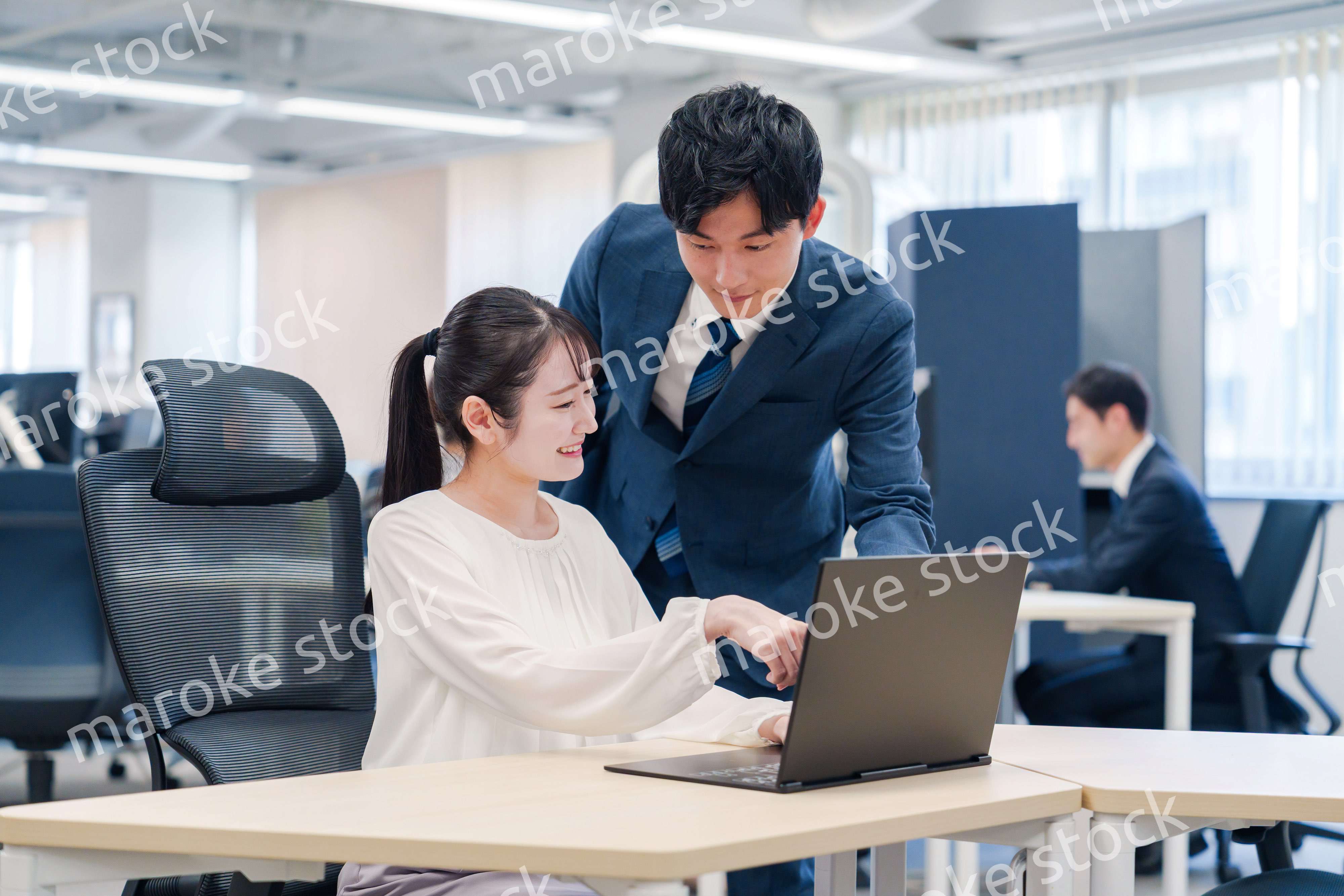 先輩社員から業務を教えてもらう新人の女性