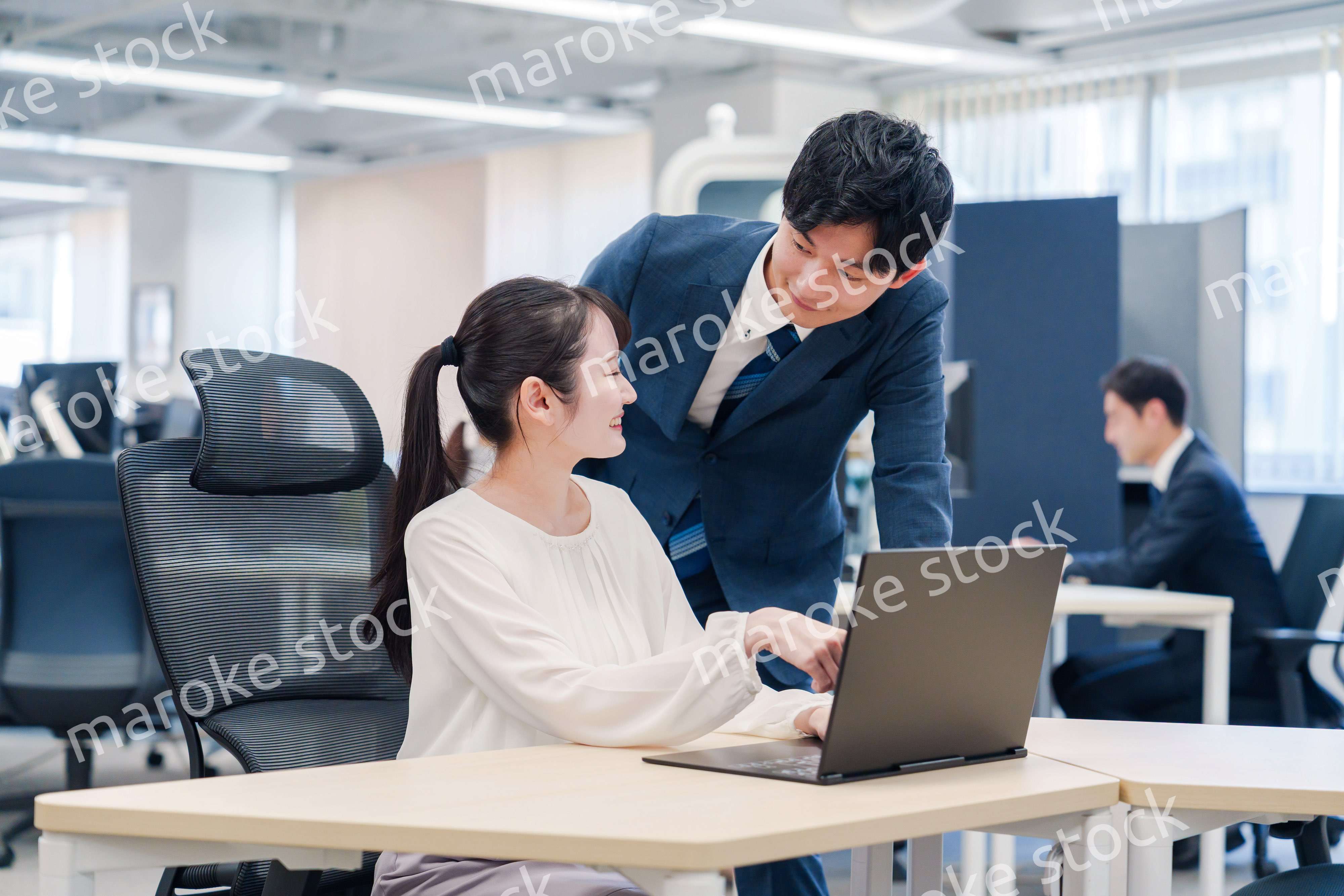 先輩社員から業務を教えてもらう新人の女性