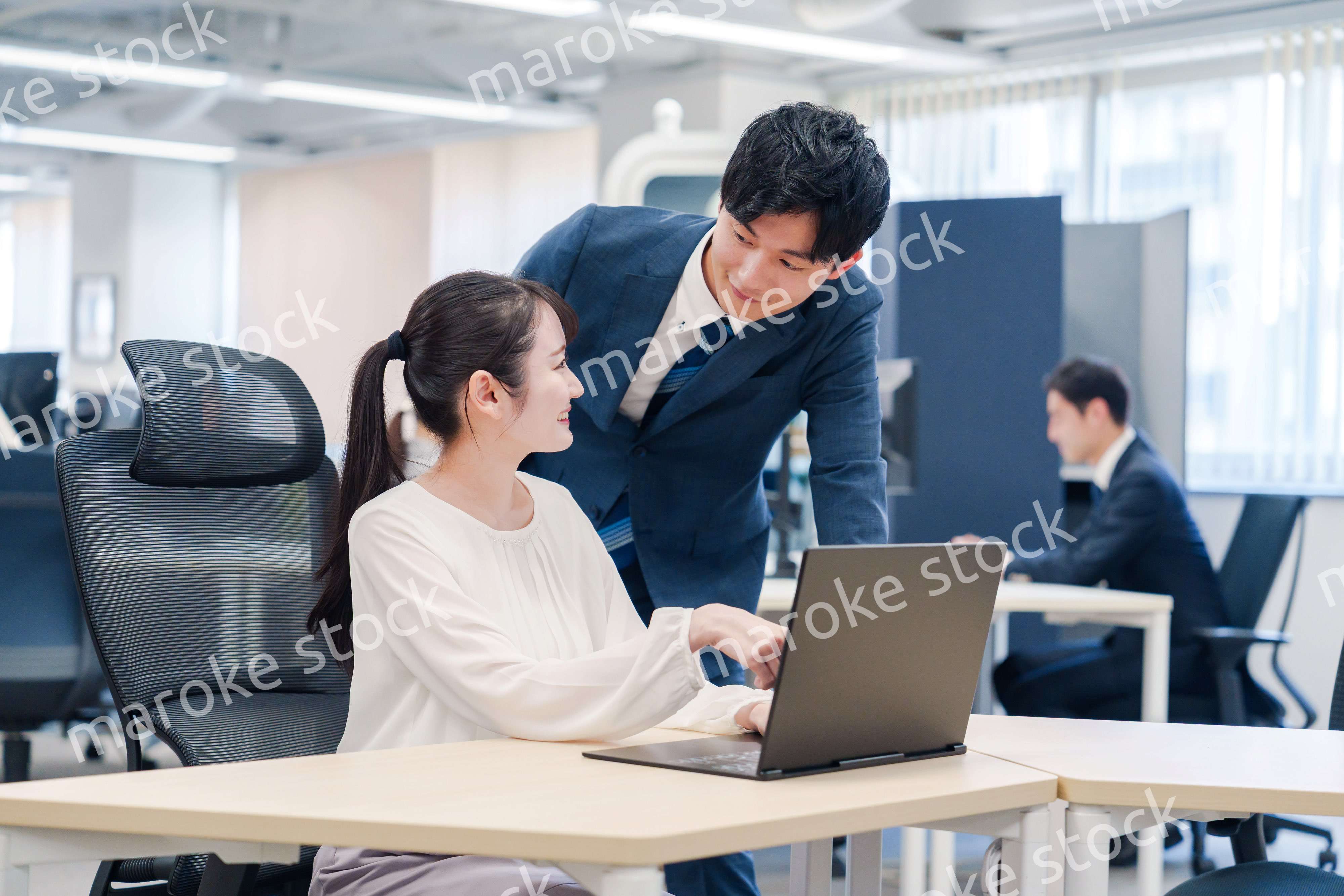 先輩社員から業務を教えてもらう新人の女性