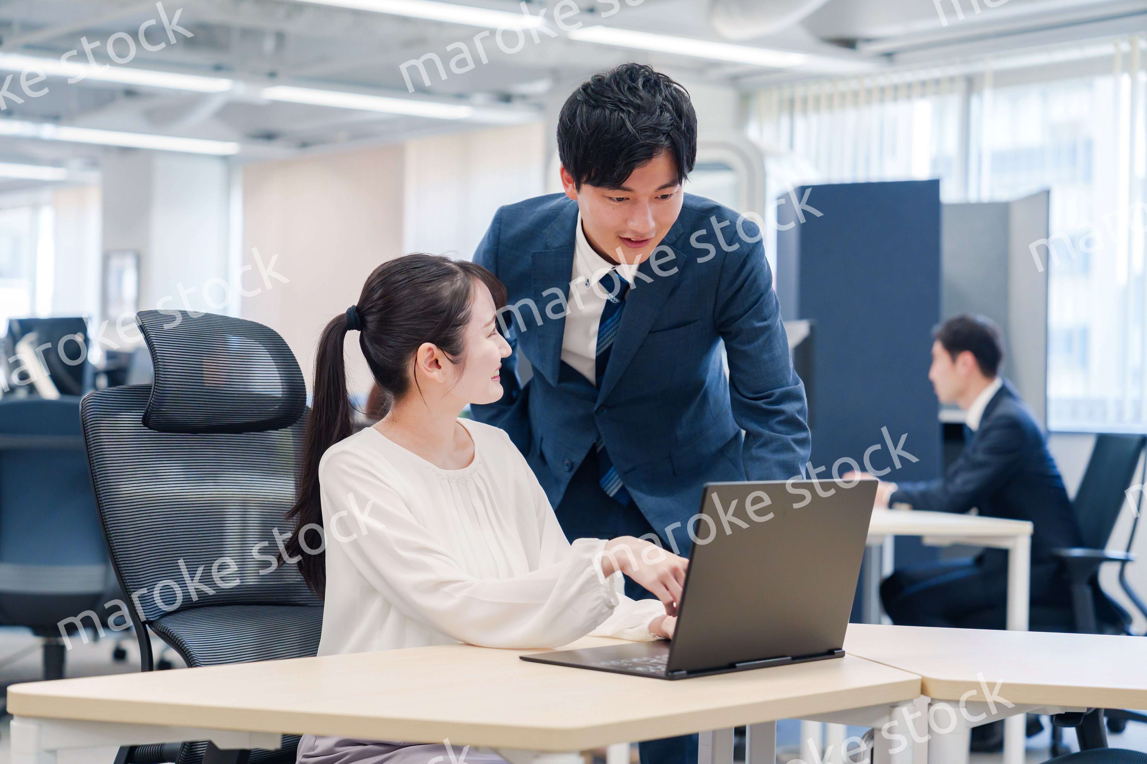 先輩社員から業務を教えてもらう新人の女性