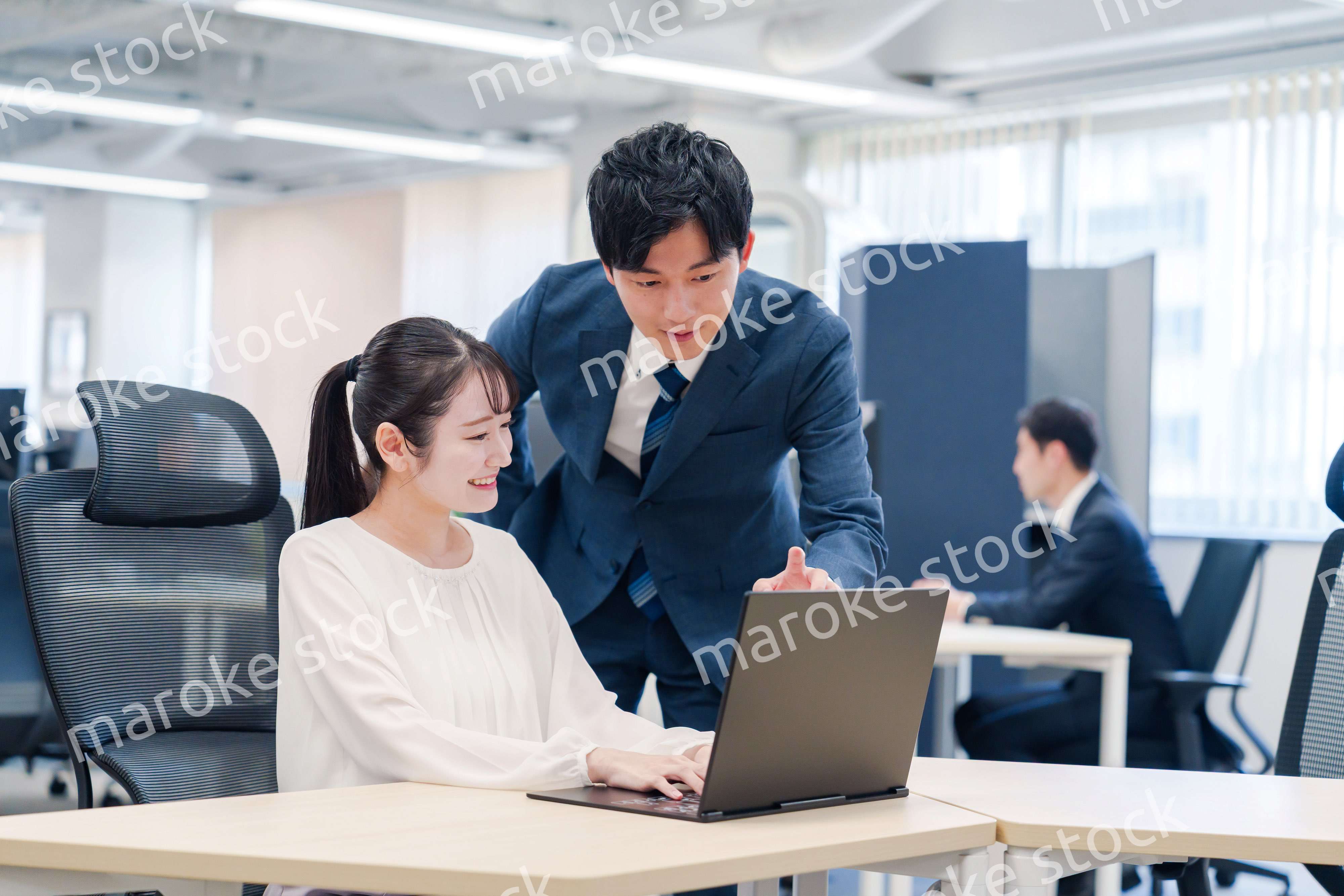 先輩社員から業務を教えてもらう新人の女性