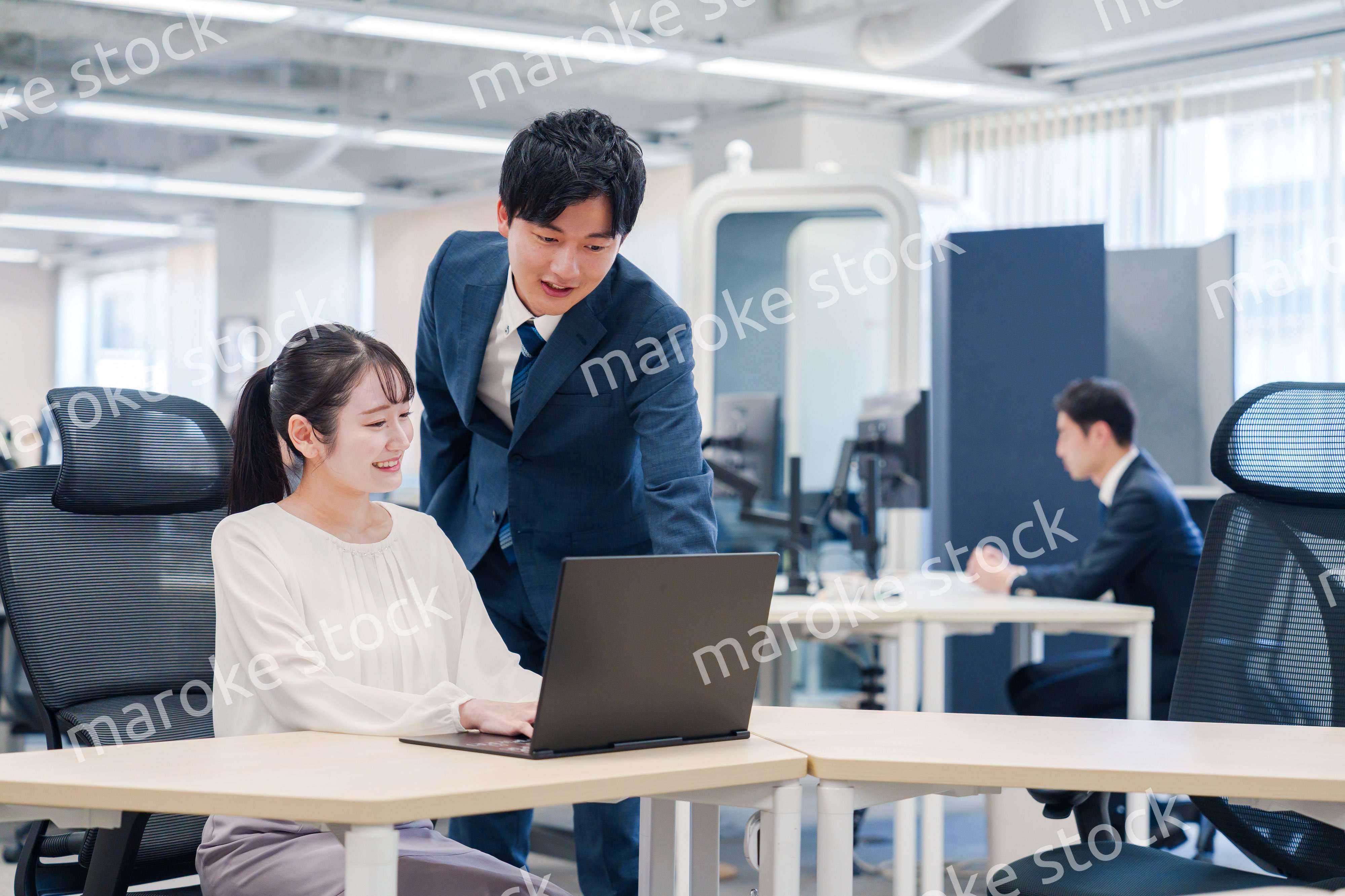 先輩社員から業務を教えてもらう新人の女性