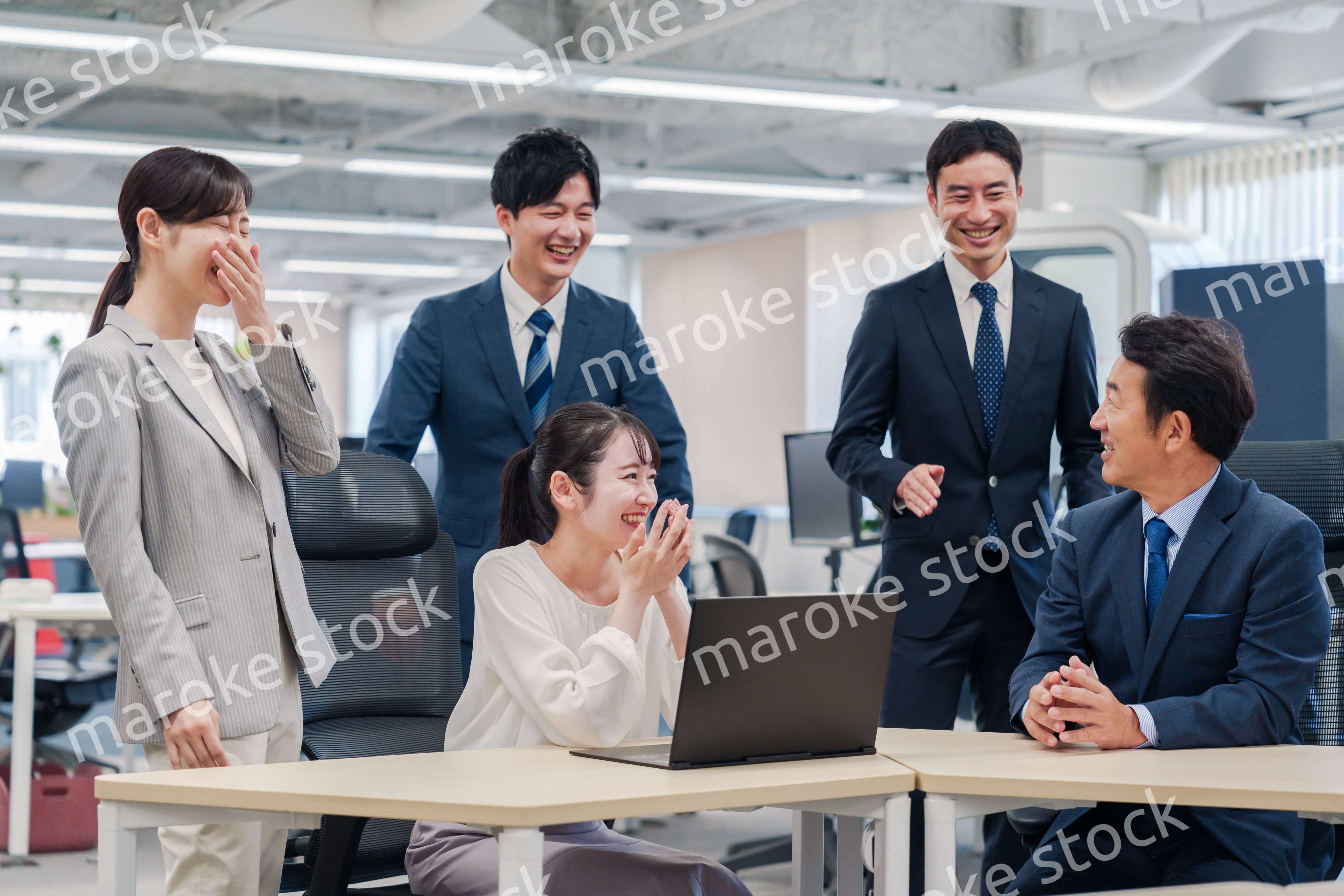 チームメンバーで非常ににこやかに仕事をするオフィスワーカー