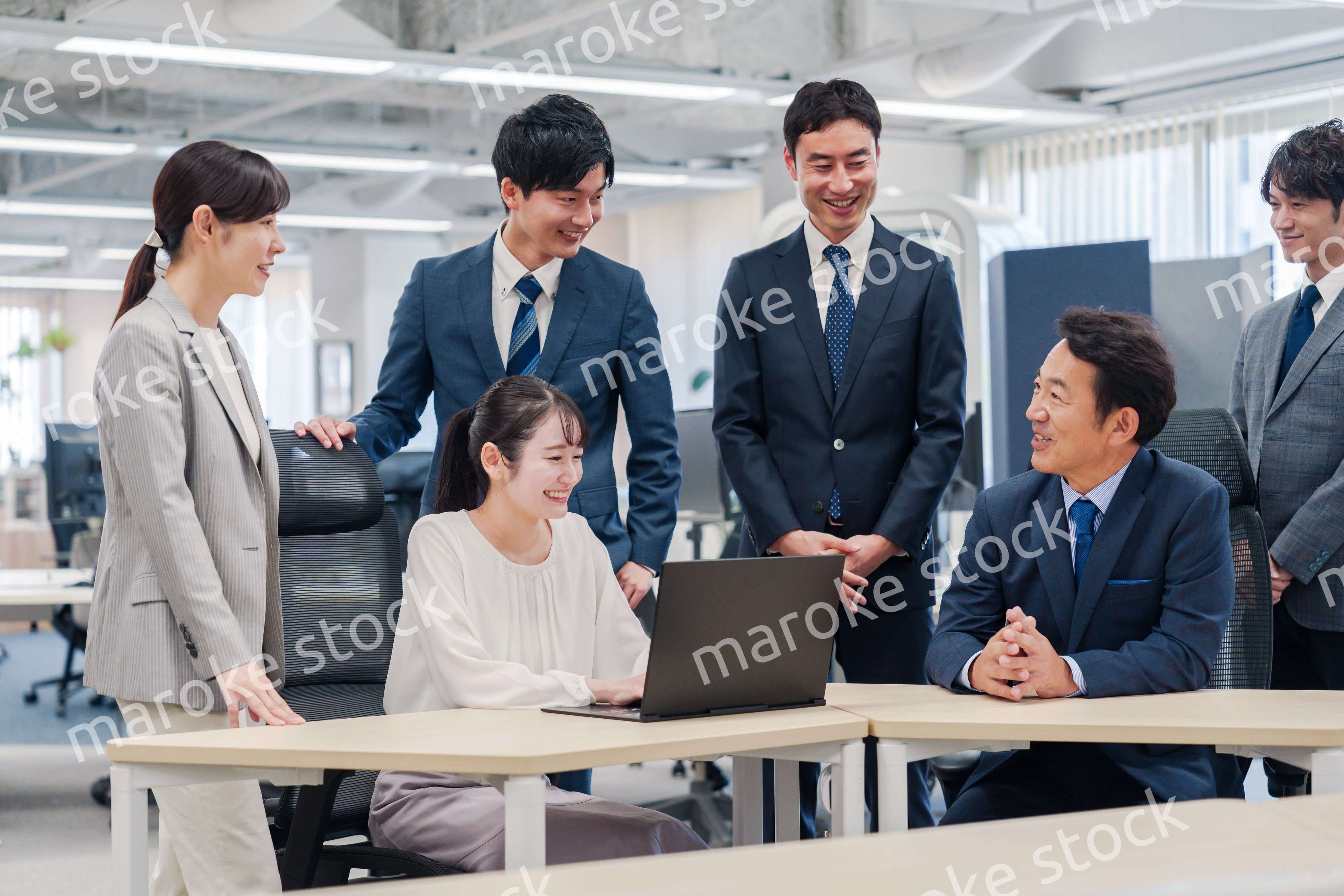 チームメンバーで非常ににこやかに仕事をするオフィスワーカー