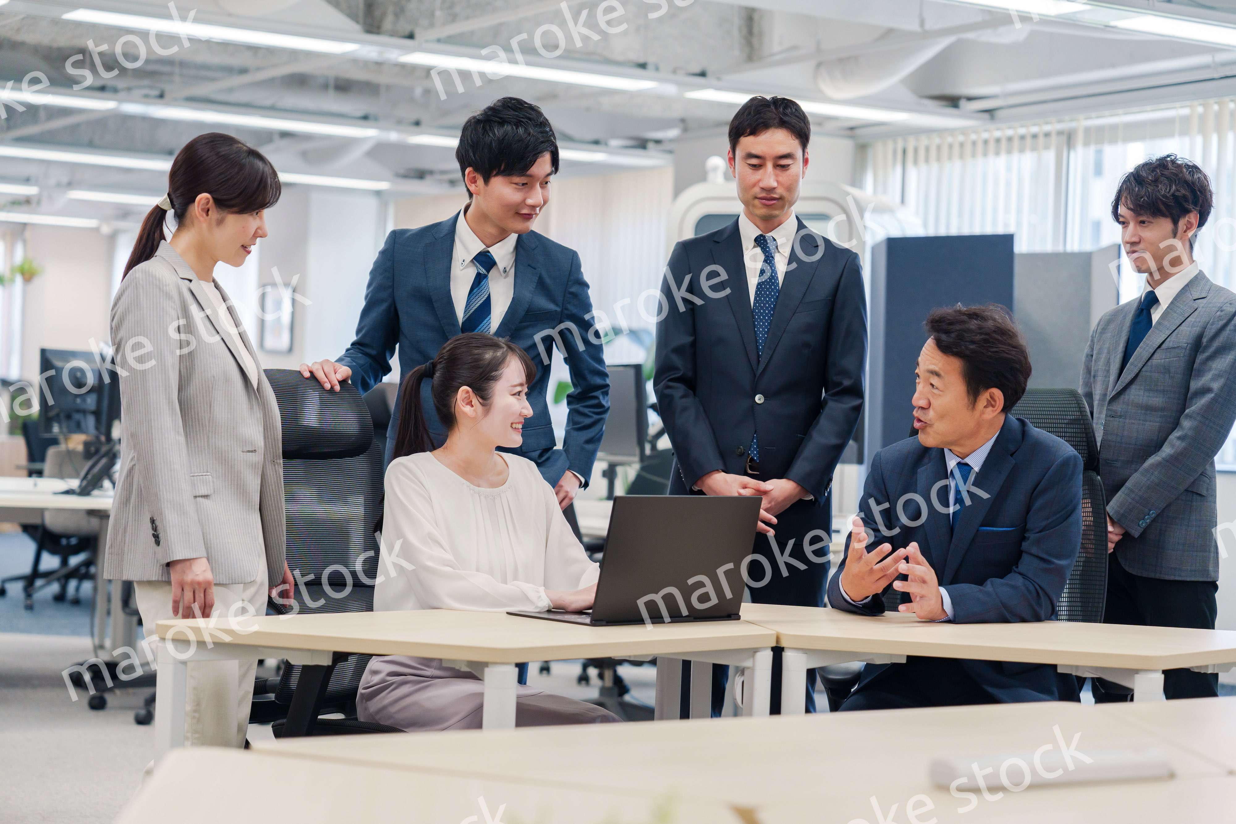 チームメンバーで非常ににこやかに仕事をするオフィスワーカー