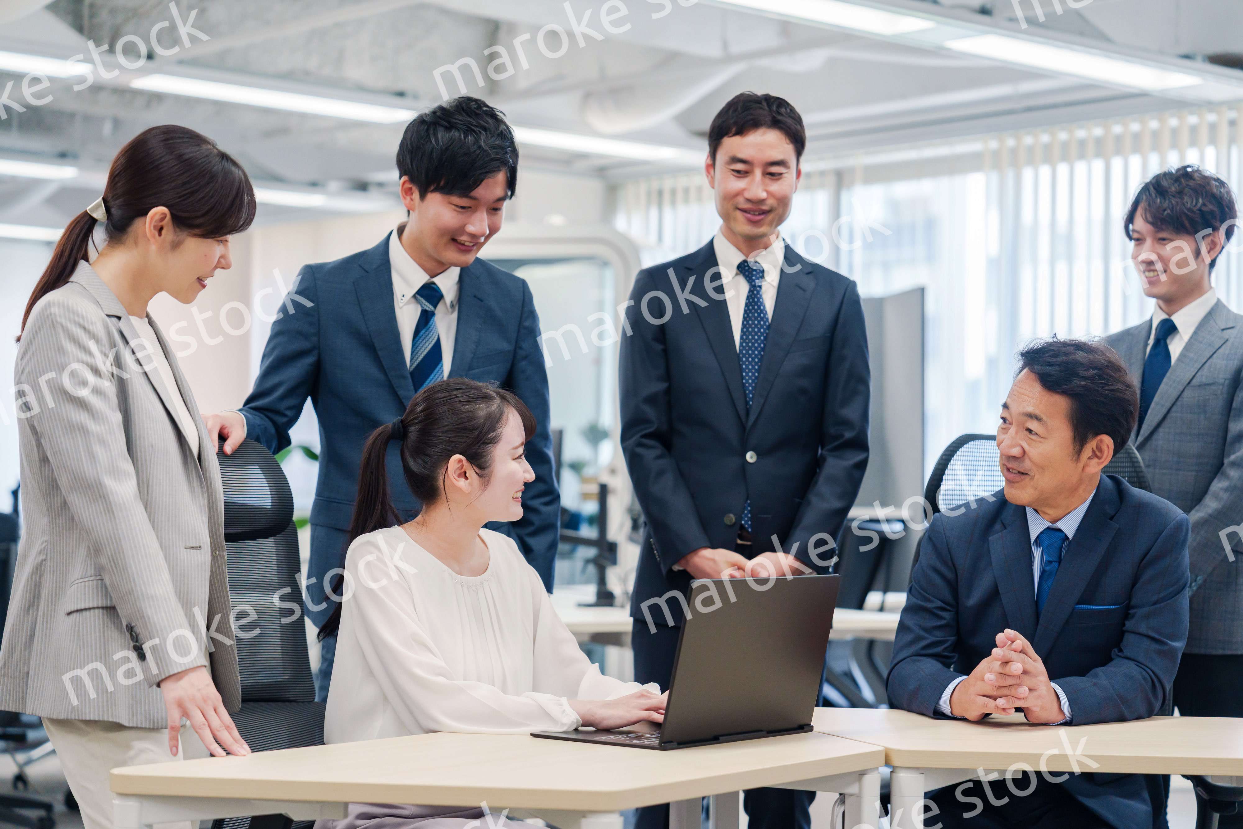 チームメンバーで非常ににこやかに仕事をするオフィスワーカー