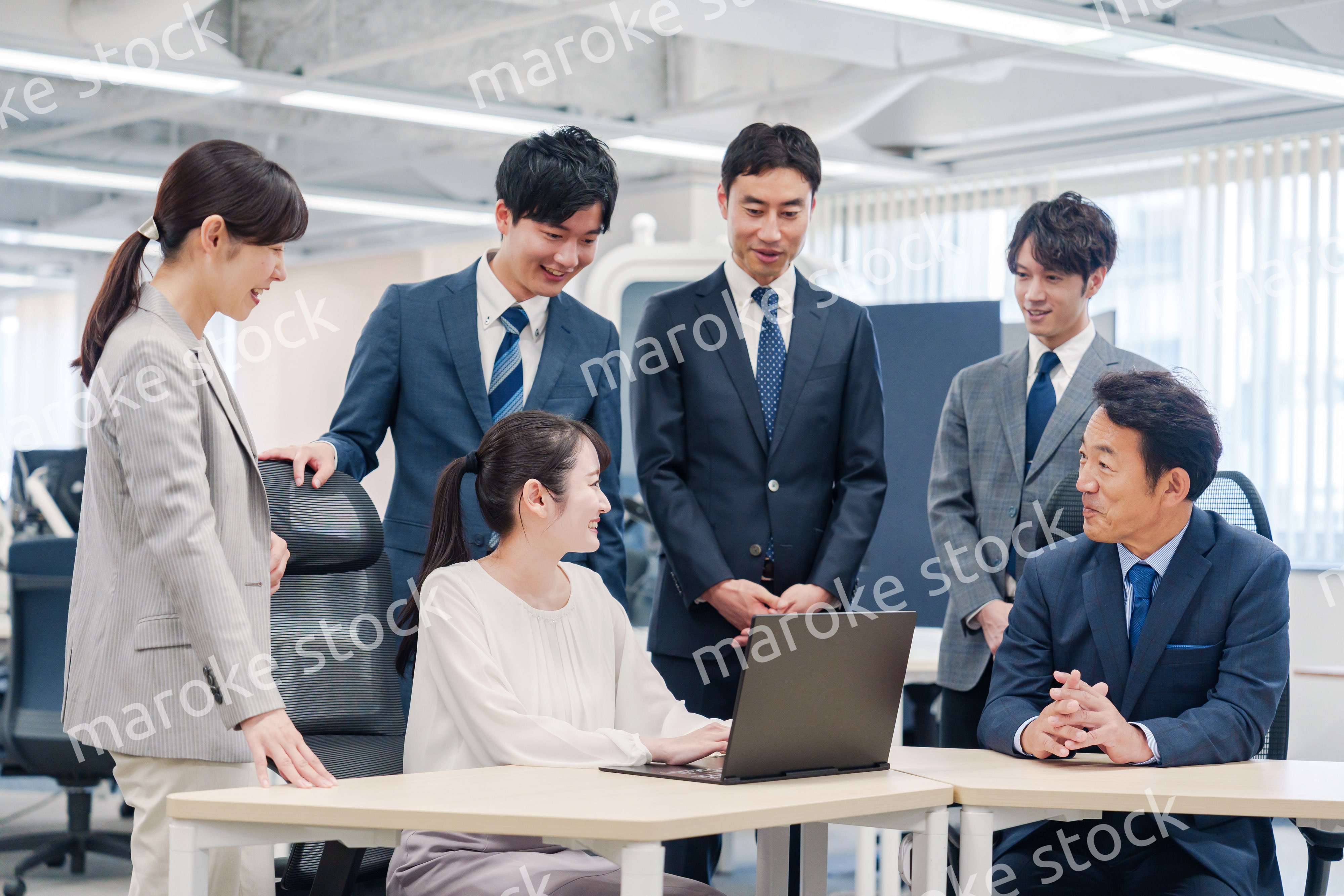 チームメンバーで非常ににこやかに仕事をするオフィスワーカー