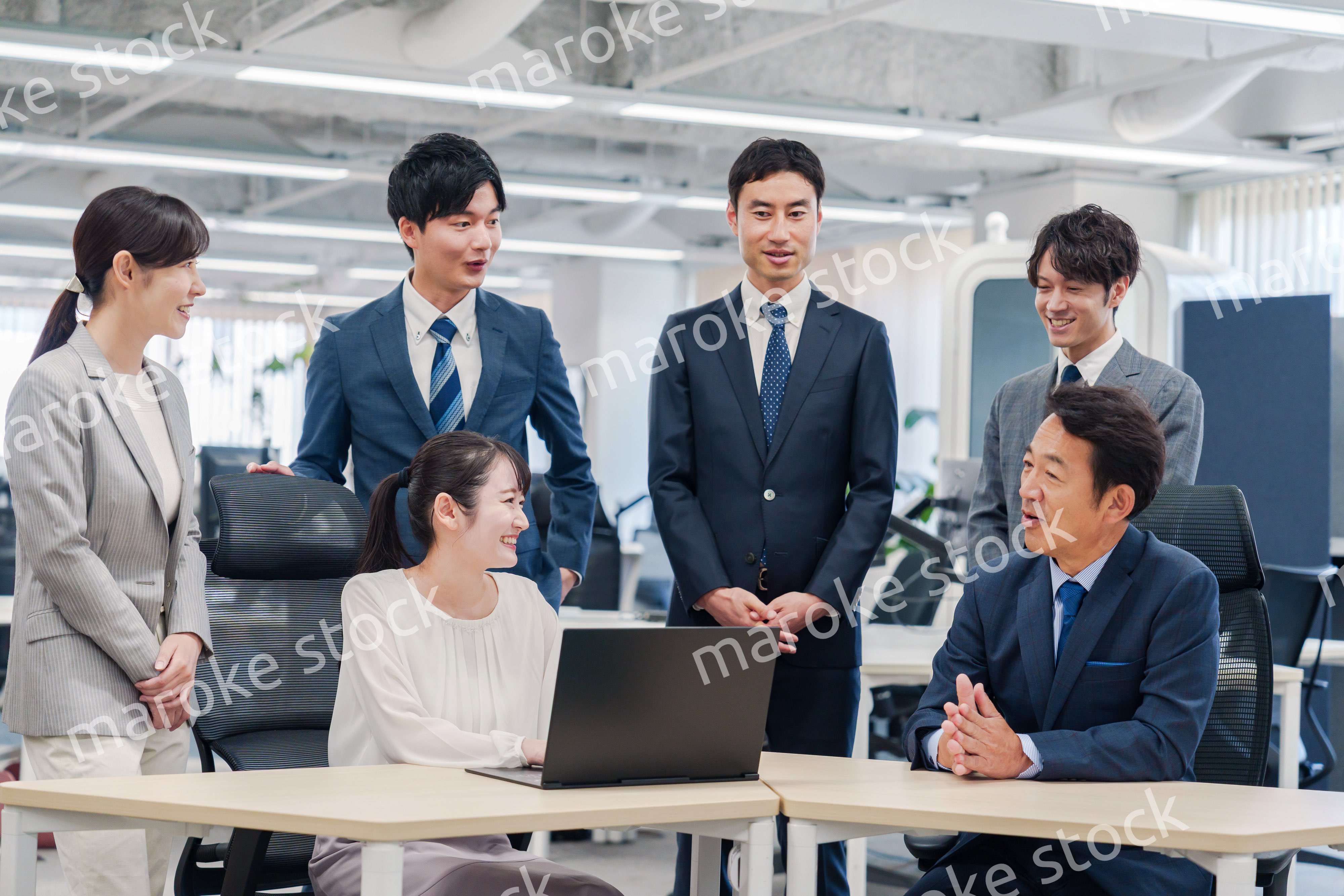 チームメンバーで非常ににこやかに仕事をするオフィスワーカー