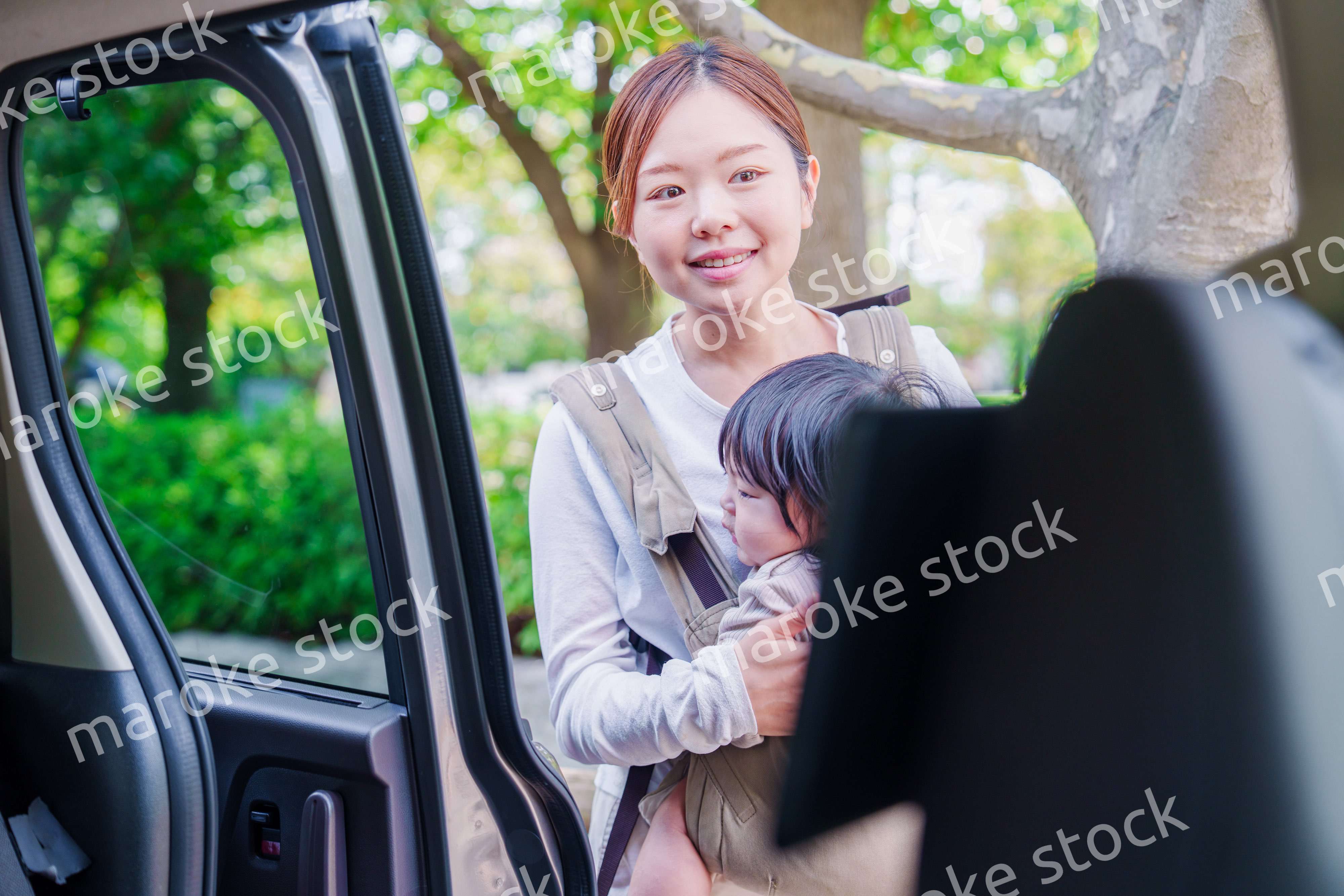 抱っこ紐で子供と一緒にタクシーに乗る女性