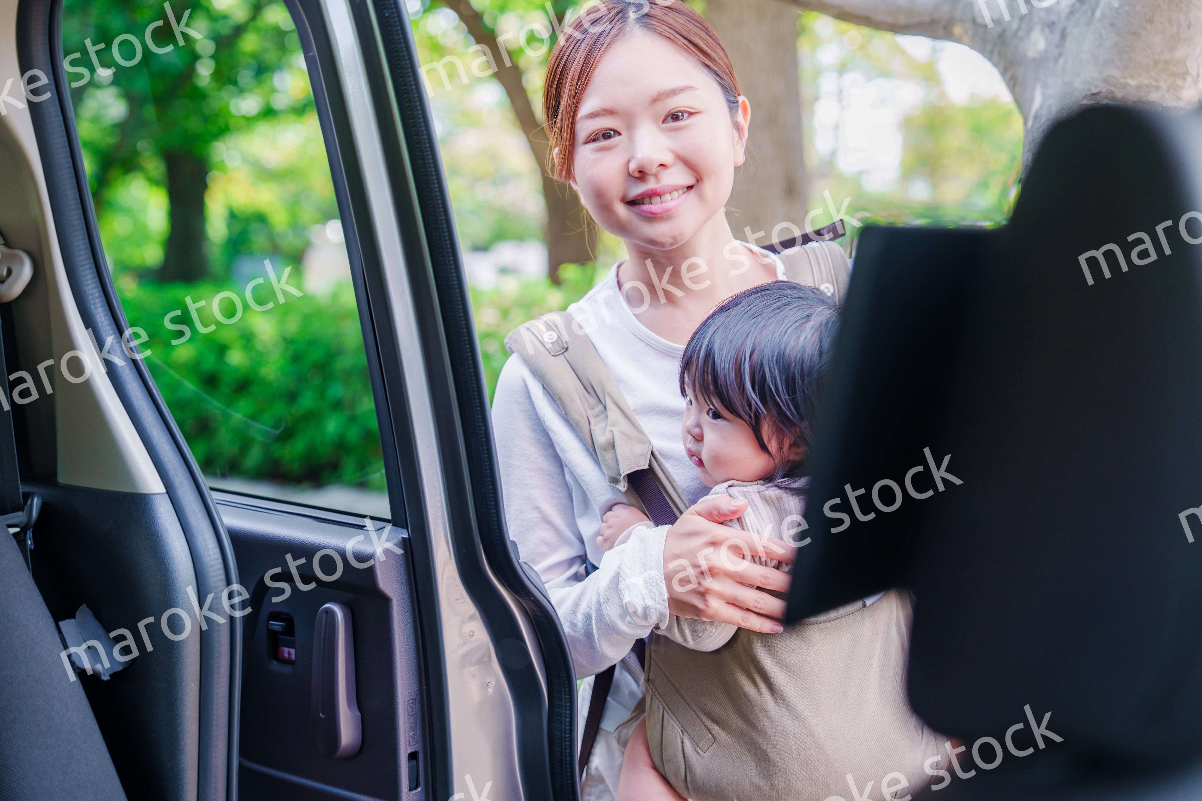 抱っこ紐で子供と一緒にタクシーに乗る女性