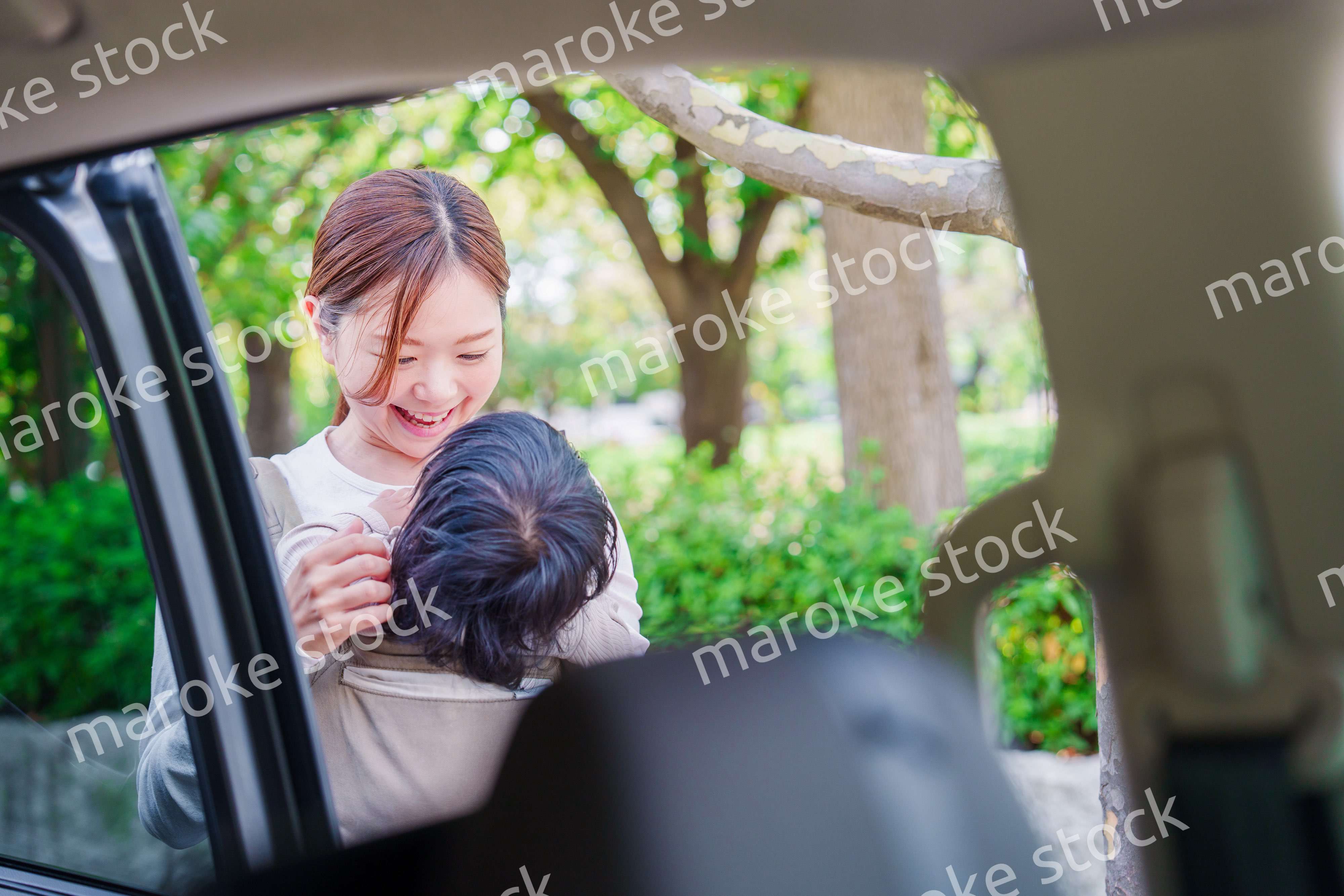 抱っこ紐で子供と一緒にタクシーに乗る女性