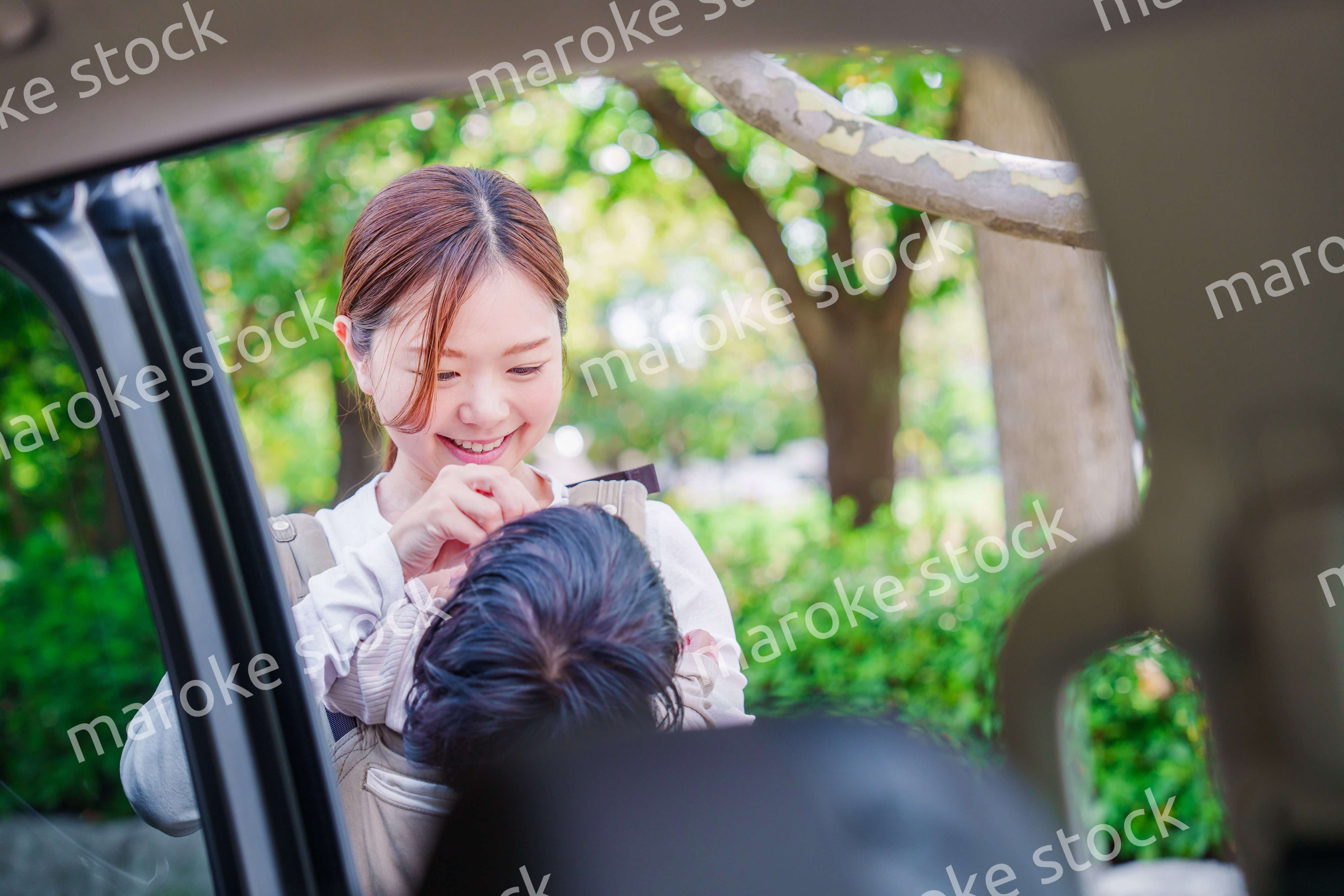 抱っこ紐で子供と一緒にタクシーに乗る女性