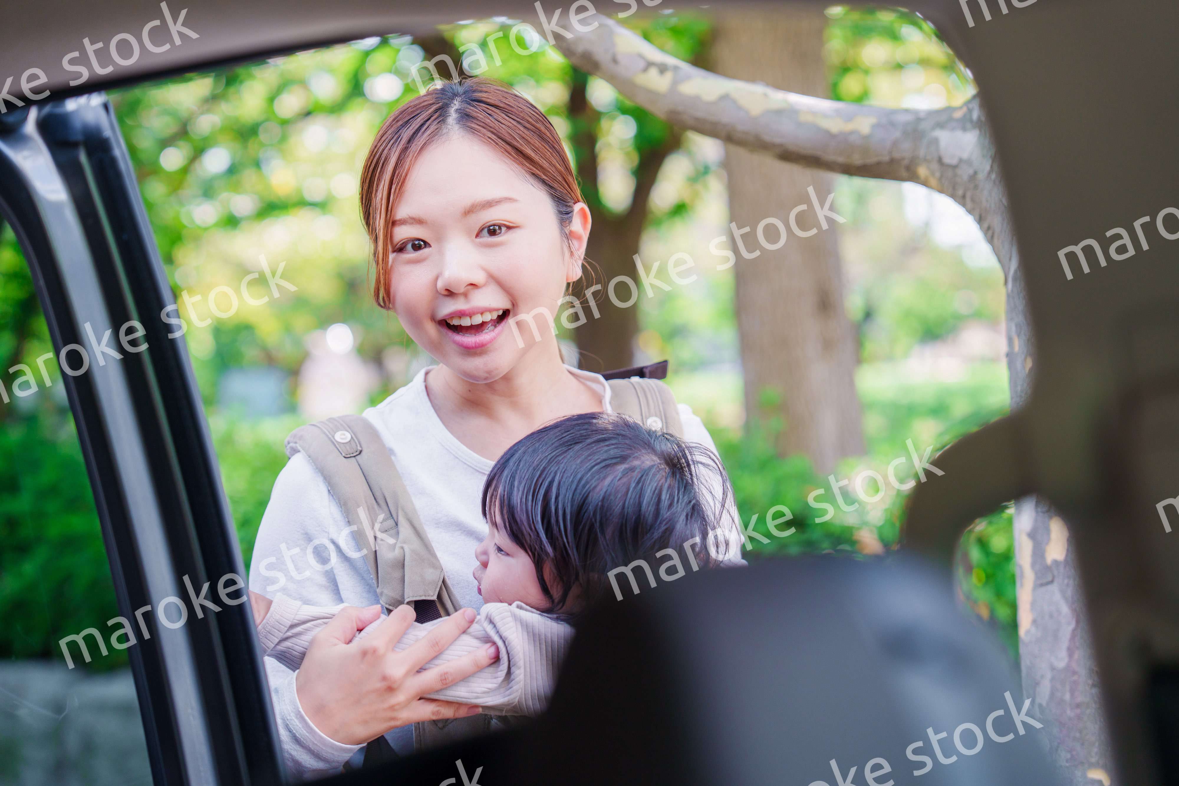 抱っこ紐で子供と一緒にタクシーに乗る女性