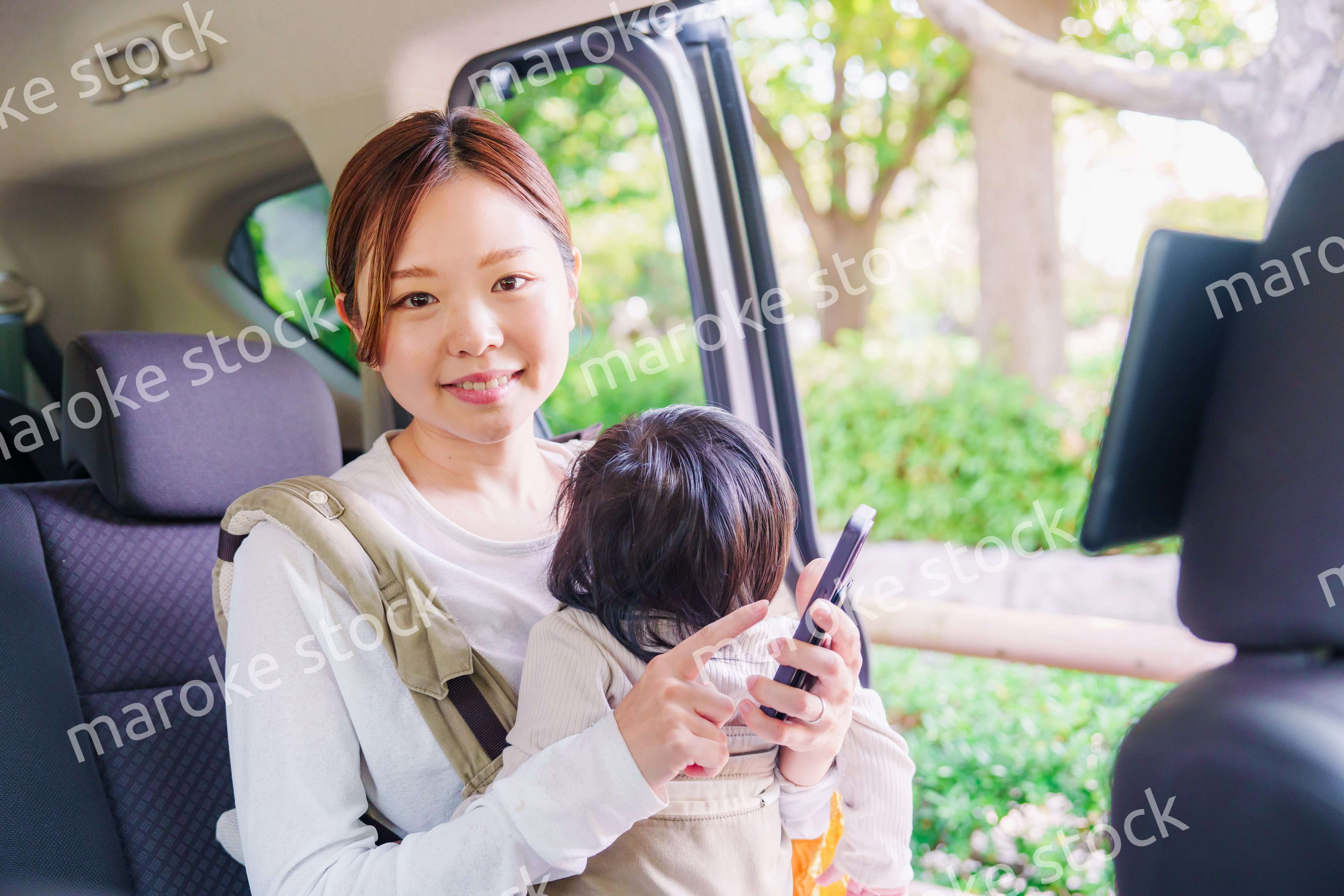 抱っこ紐で子供と一緒にタクシーに乗る女性