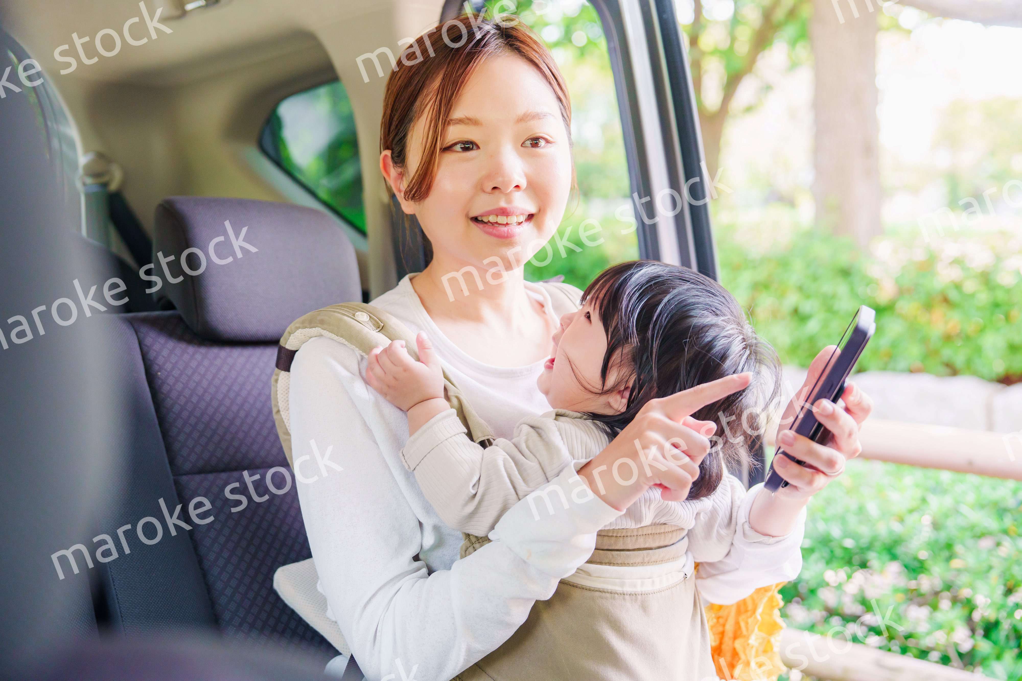 抱っこ紐で子供と一緒にタクシーに乗る女性