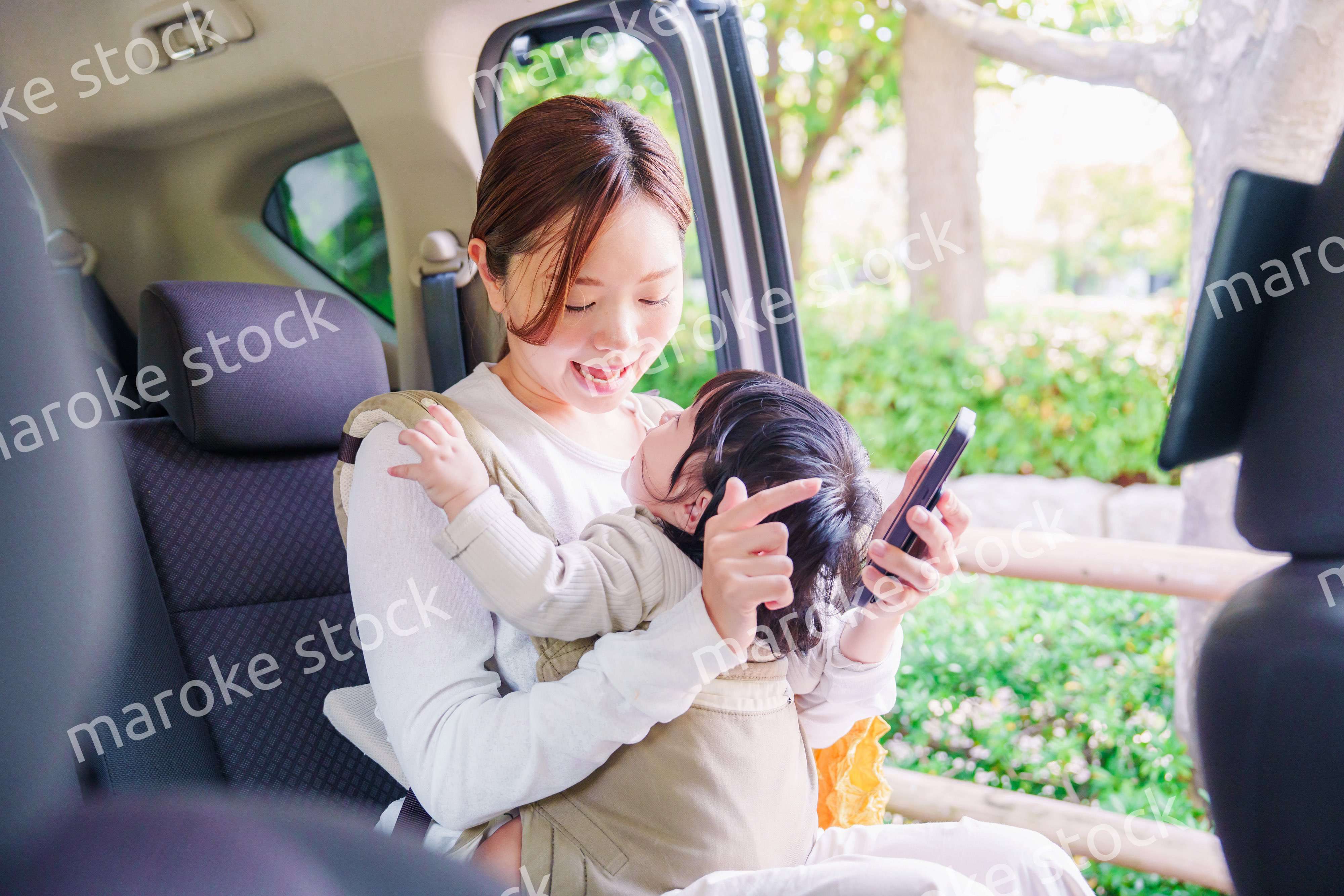 抱っこ紐で子供と一緒にタクシーに乗る女性