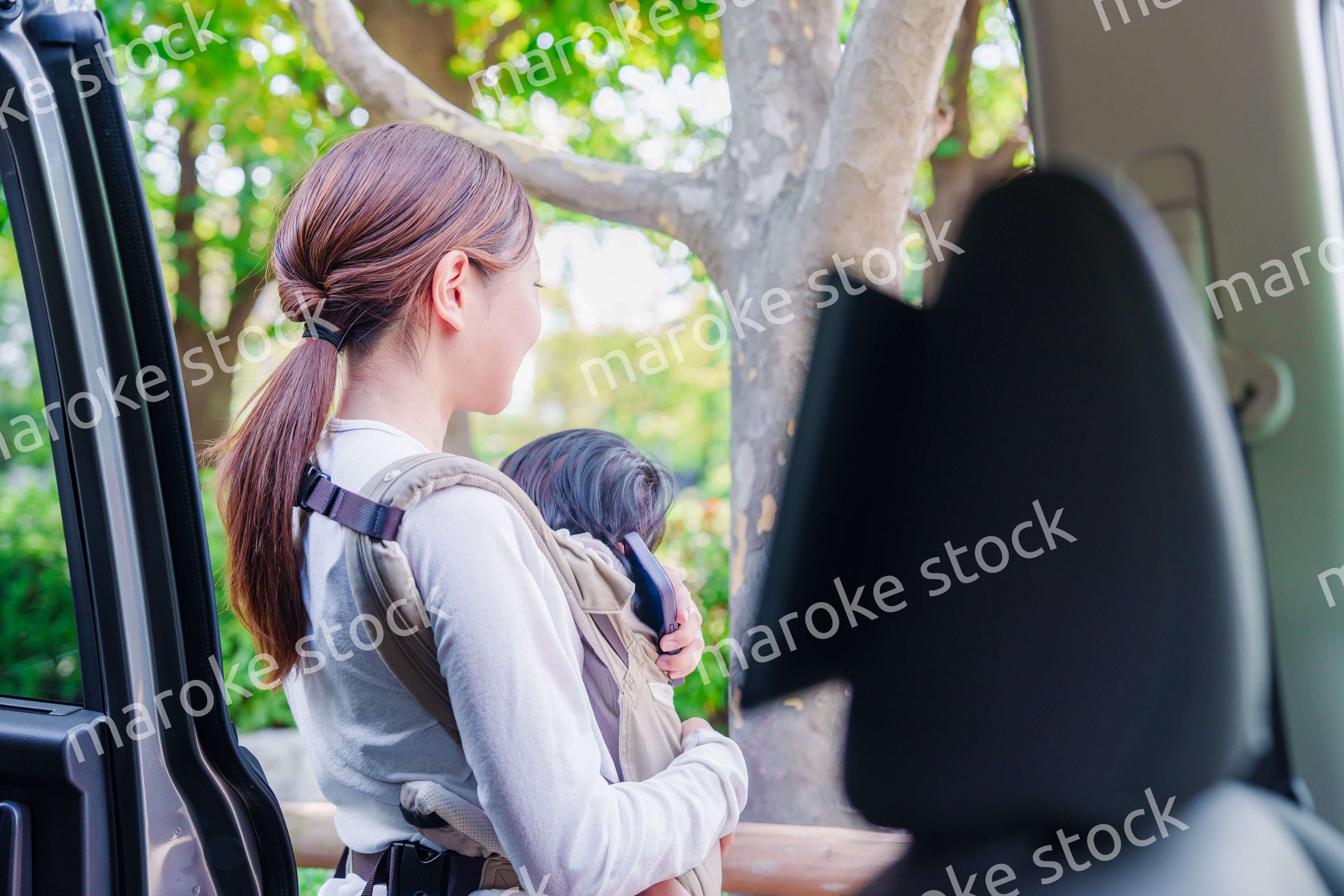 抱っこ紐で子供と一緒にタクシーに乗る女性