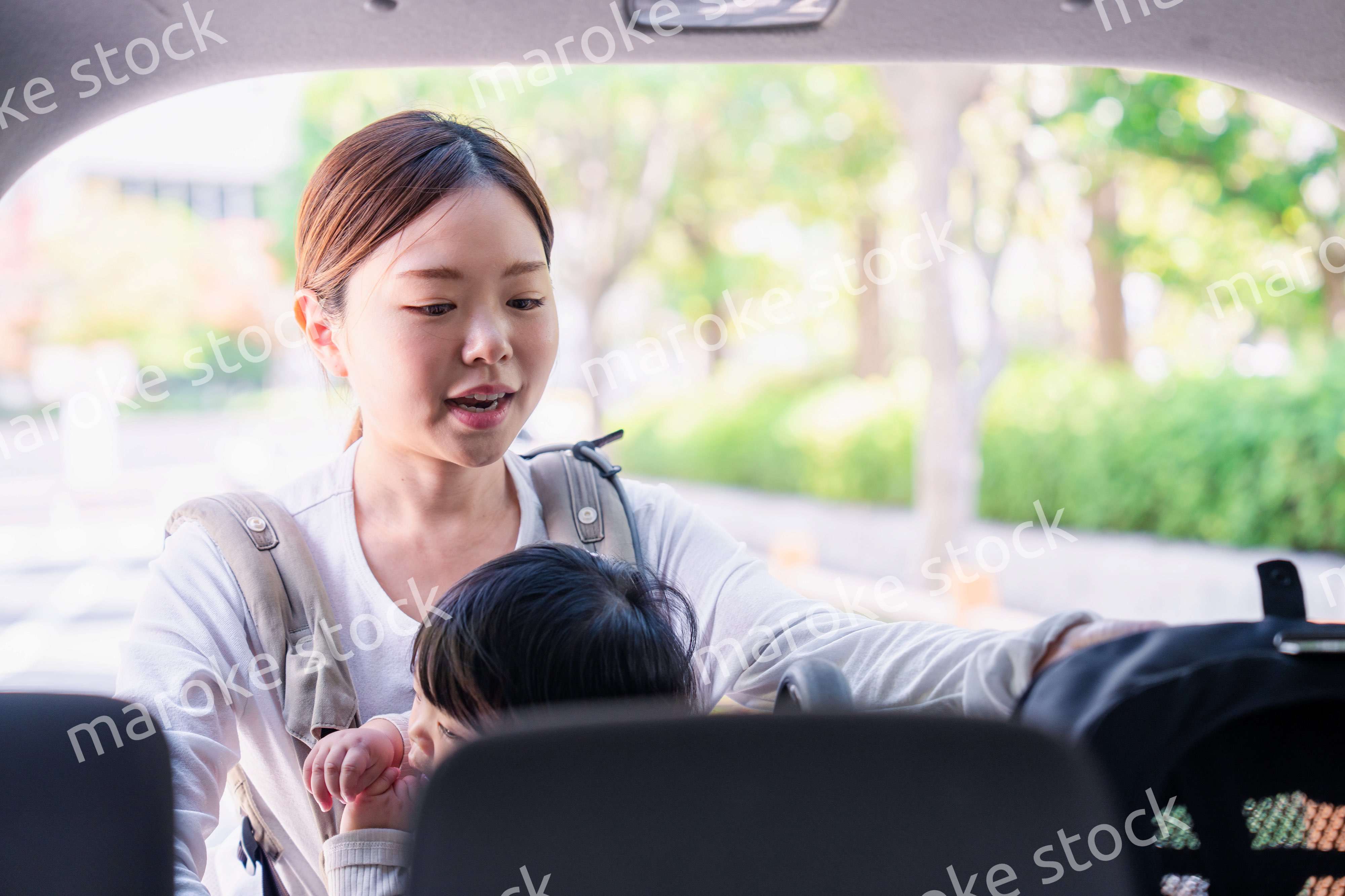 抱っこ紐をして車でお出かけをするお母さん
