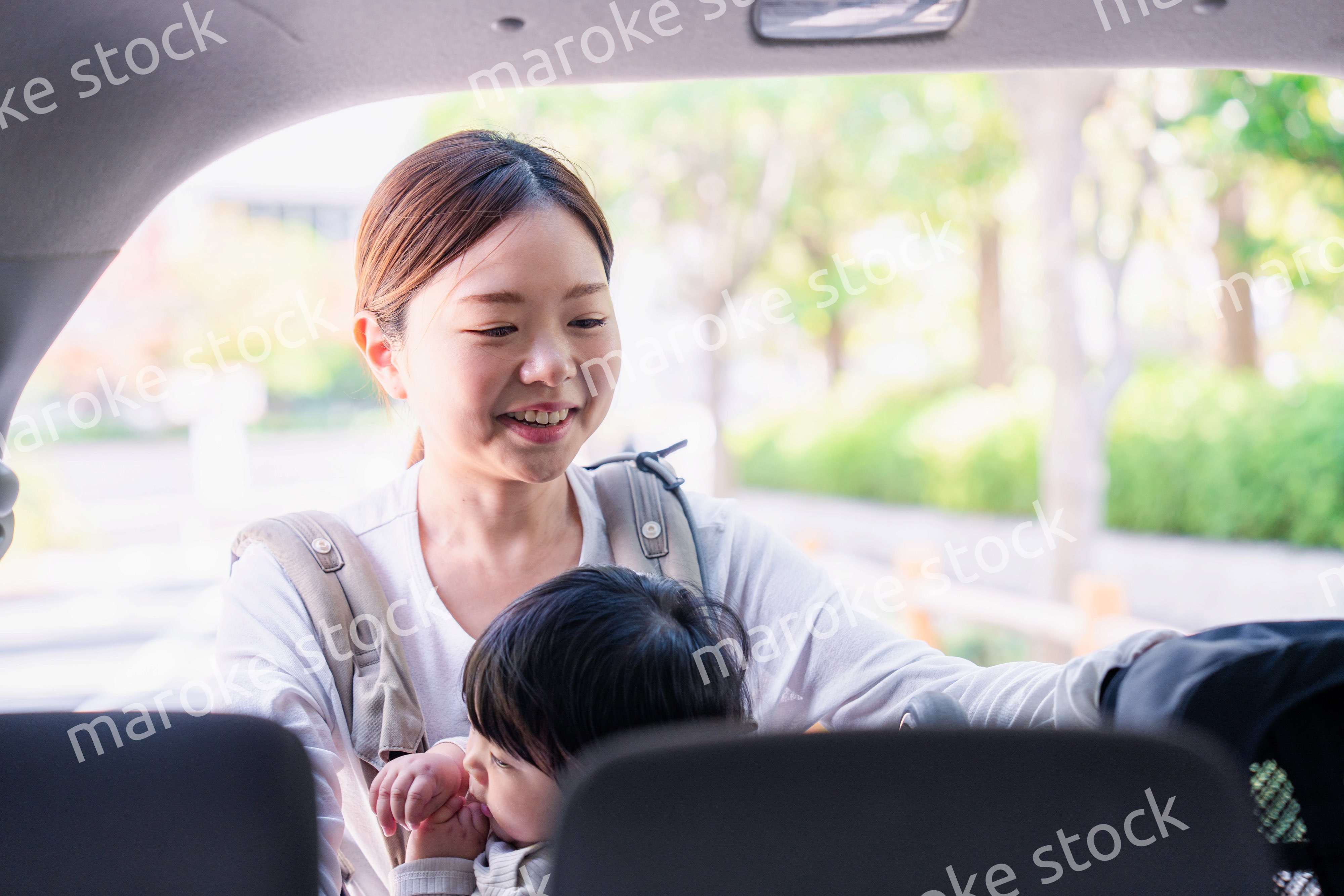 抱っこ紐をして車でお出かけをするお母さん