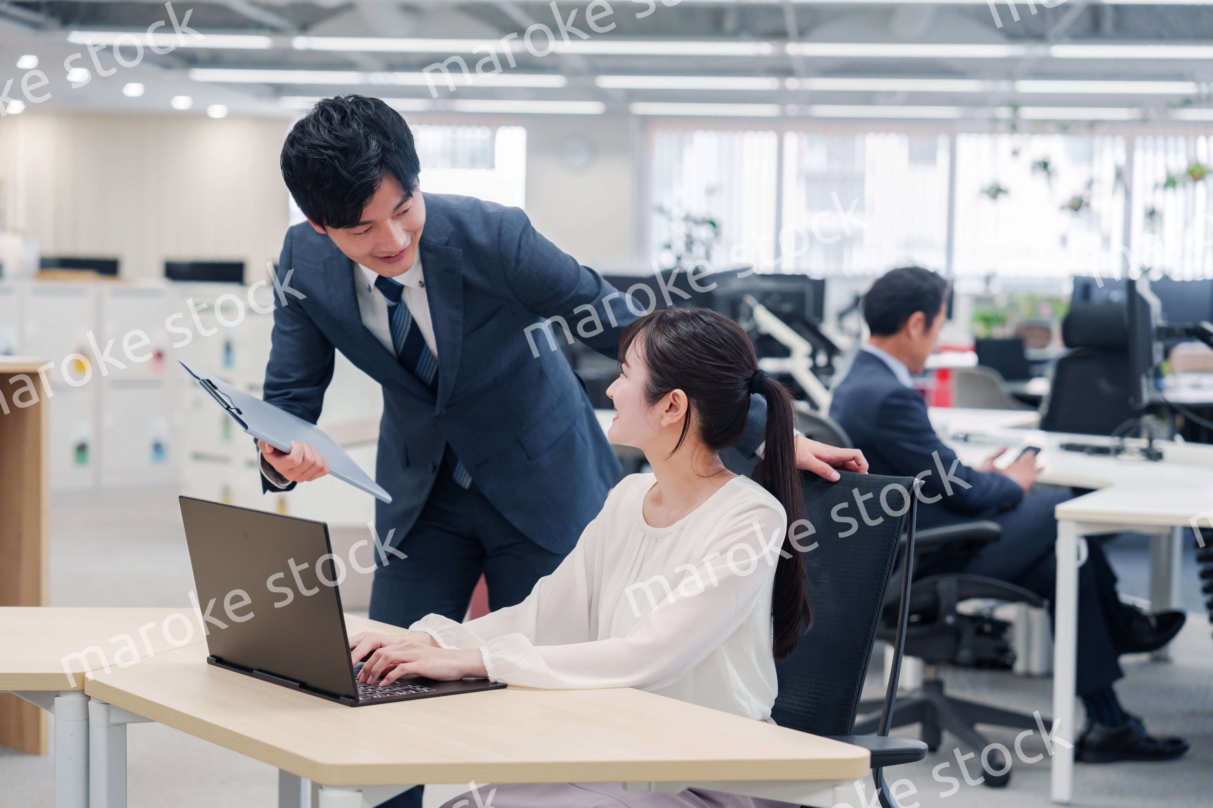 オフィスのデスクで打ち合わせをする男女のビジネスパーソン