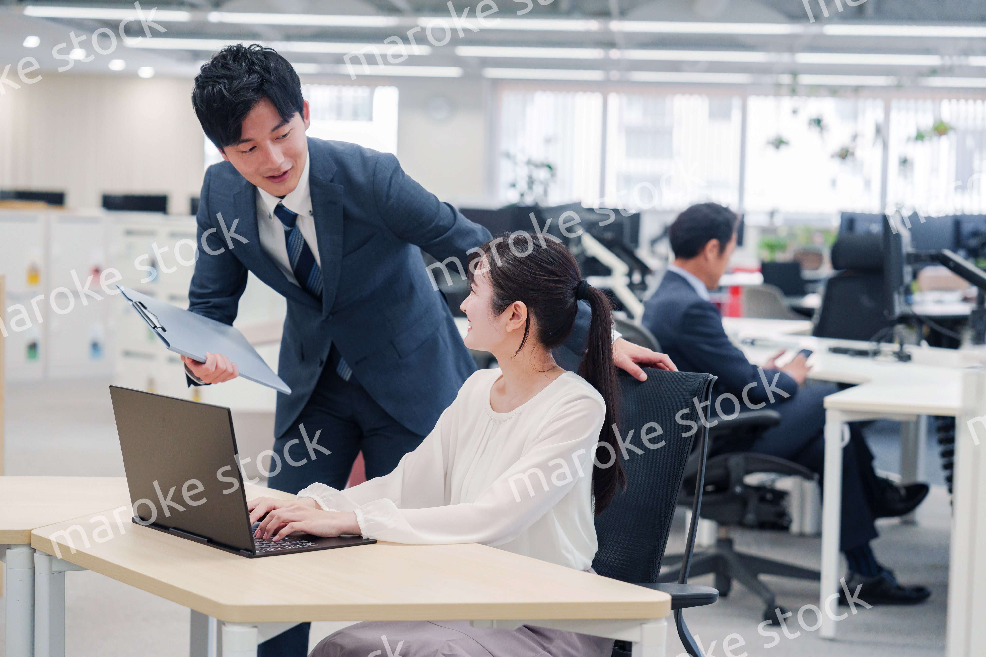 オフィスのデスクで打ち合わせをする男女のビジネスパーソン