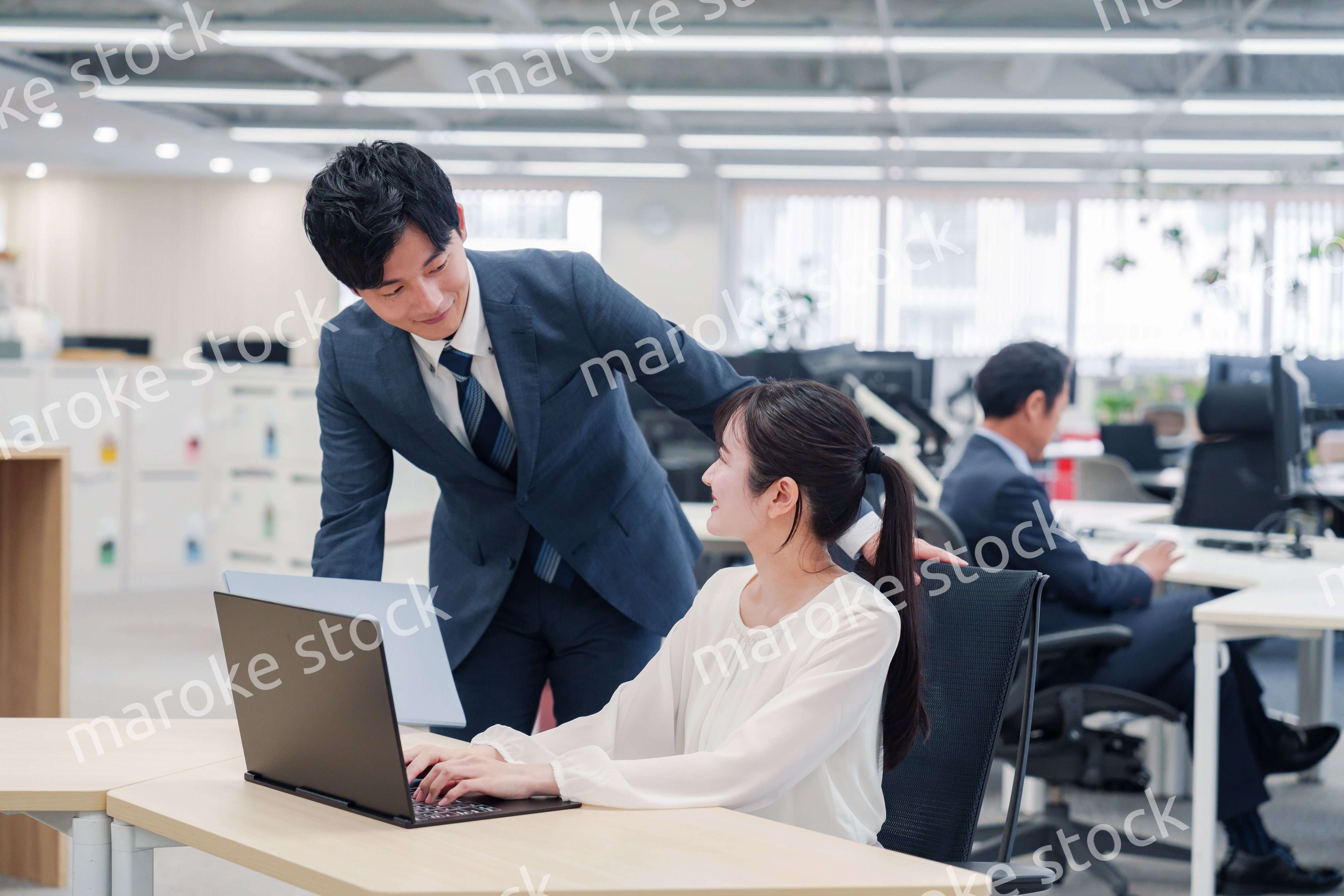 オフィスのデスクで打ち合わせをする男女のビジネスパーソン