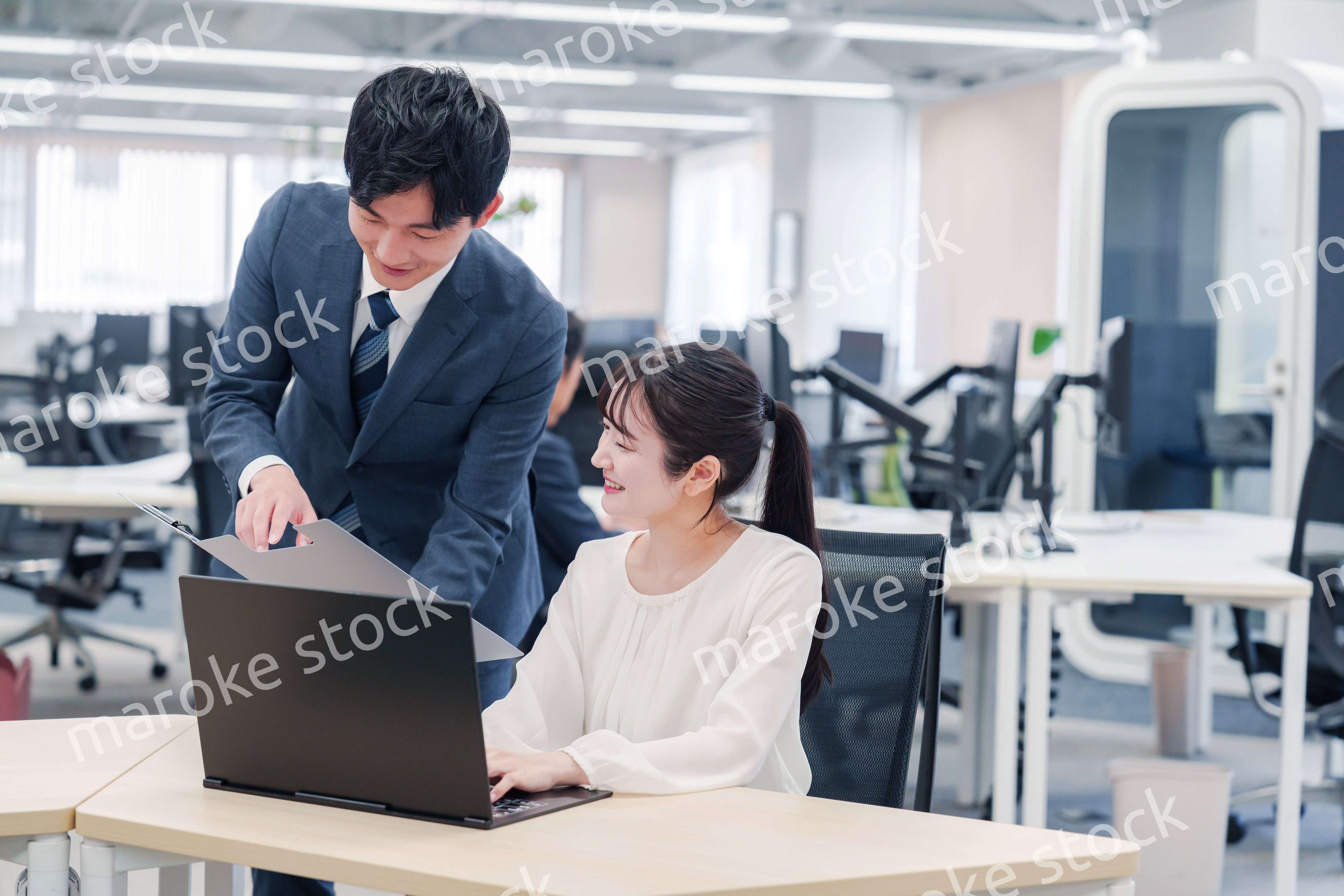 オフィスのデスクで打ち合わせをする男女のビジネスパーソン