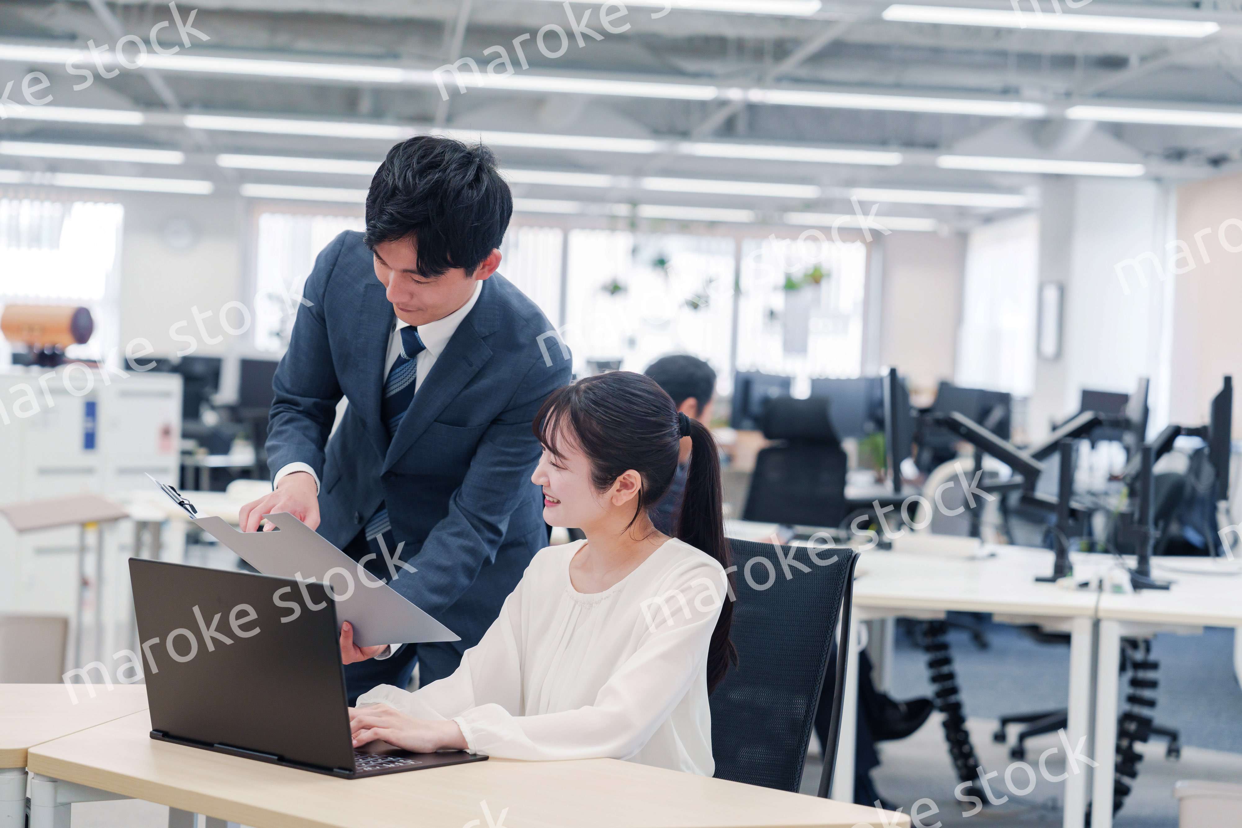 オフィスのデスクで打ち合わせをする男女のビジネスパーソン