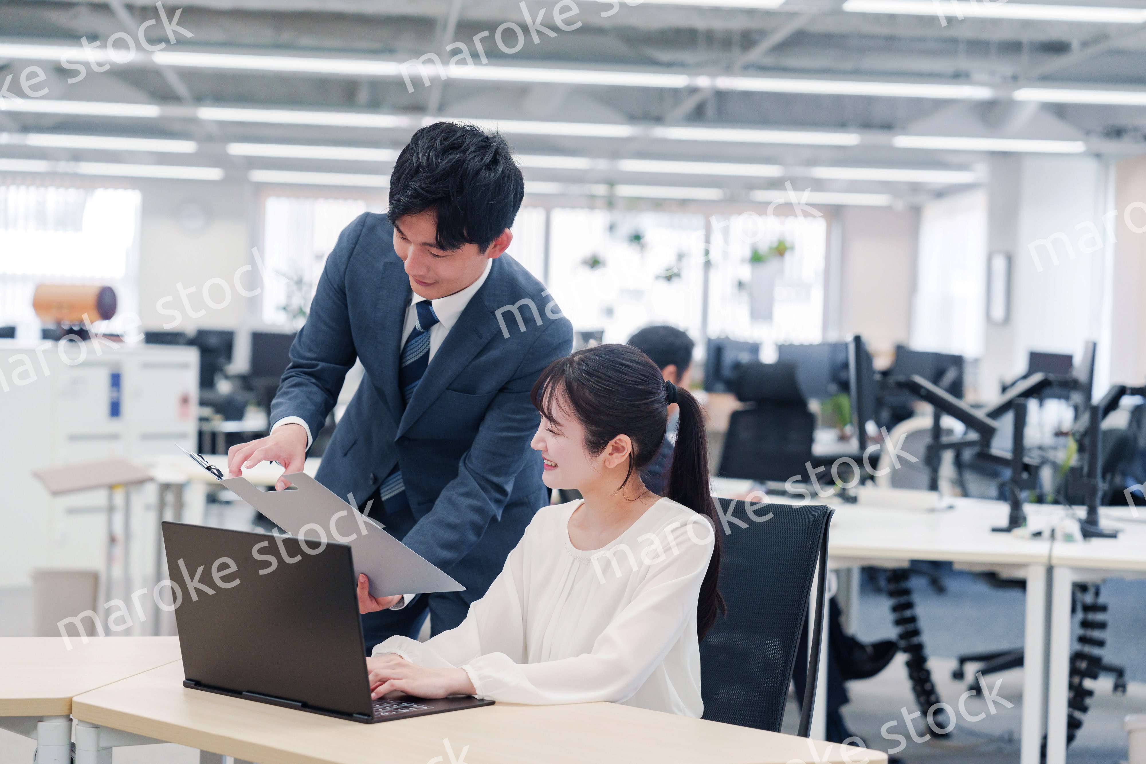 オフィスのデスクで打ち合わせをする男女のビジネスパーソン