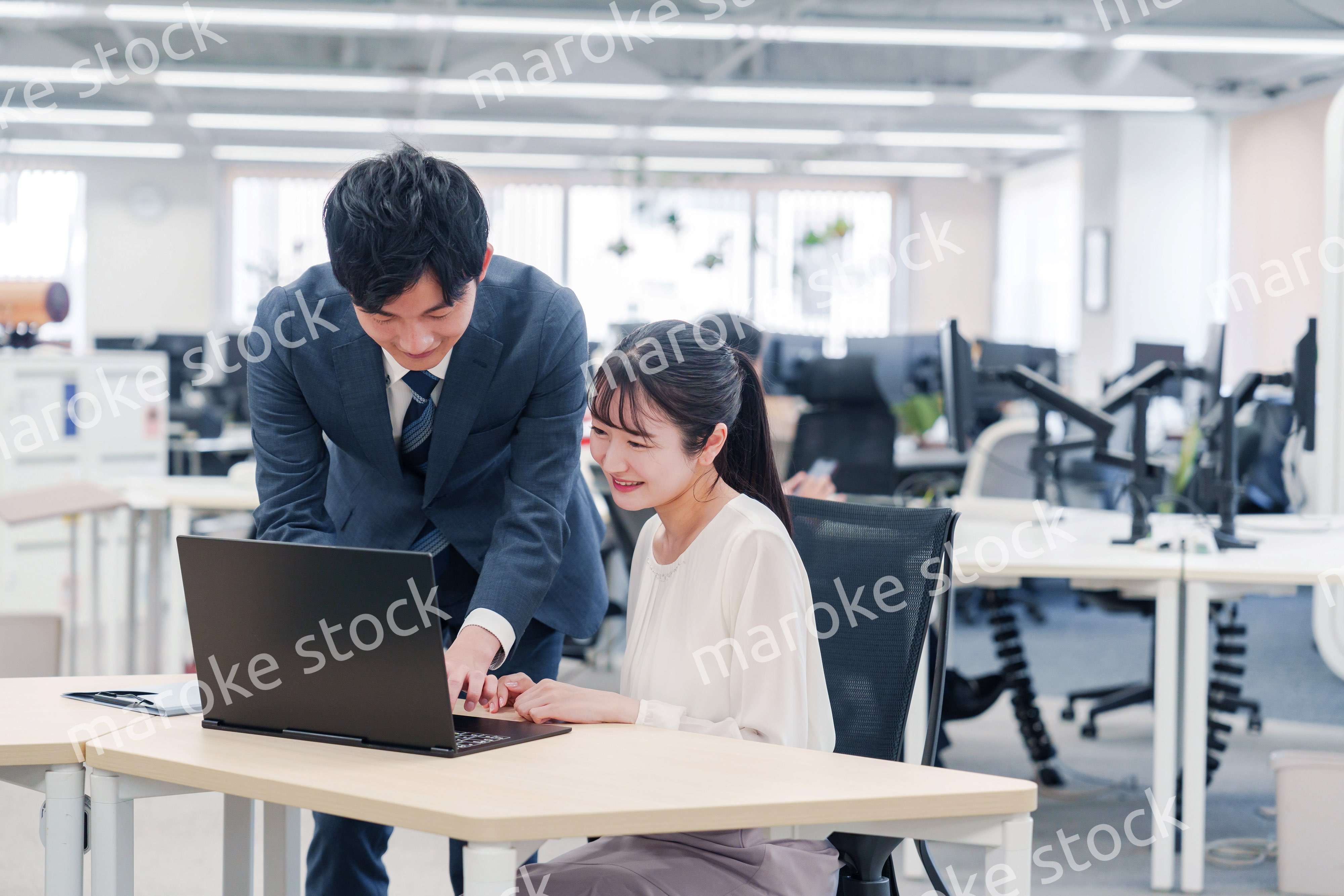 オフィスのデスクで打ち合わせをする男女のビジネスパーソン