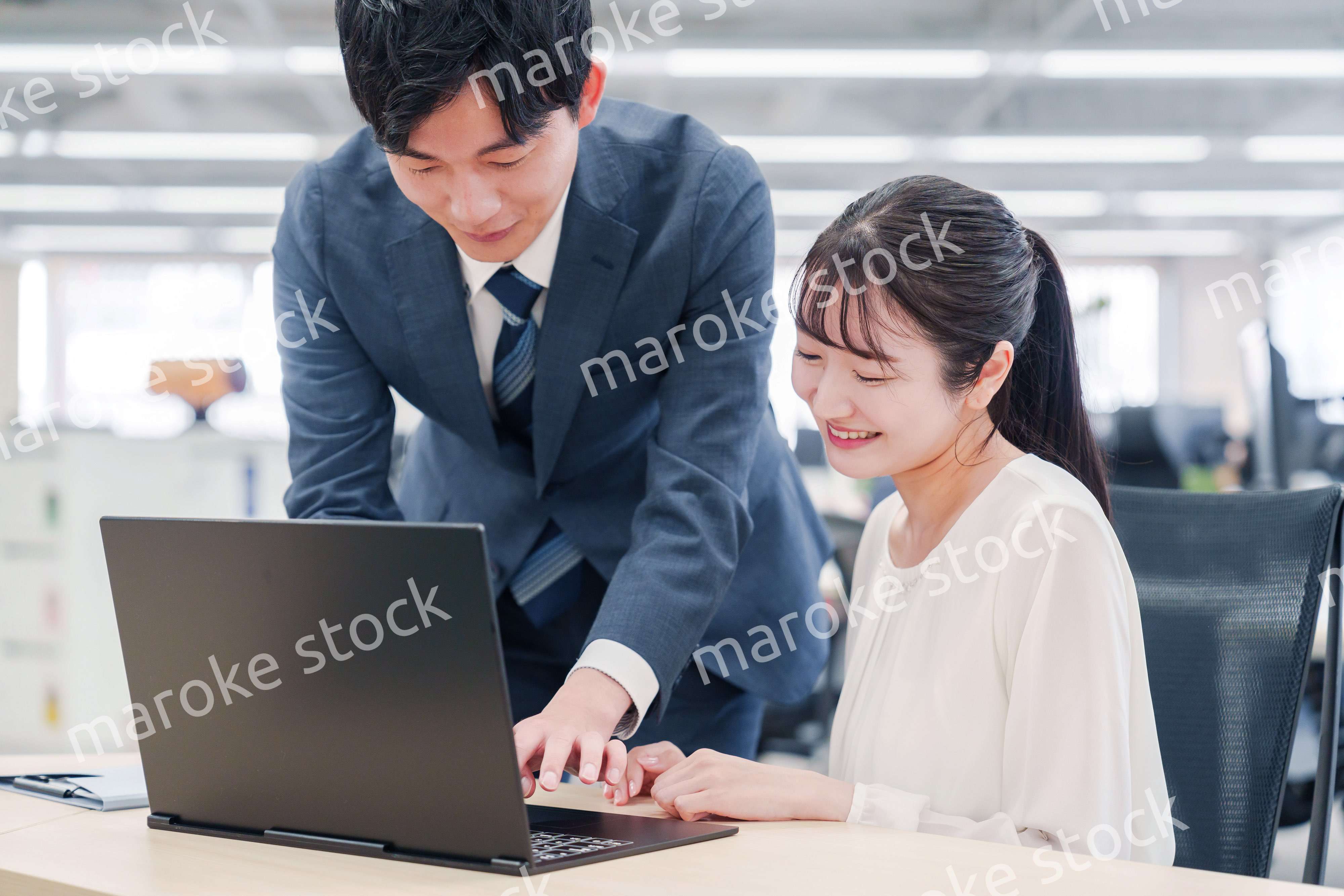 オフィスのデスクで打ち合わせをする男女のビジネスパーソン