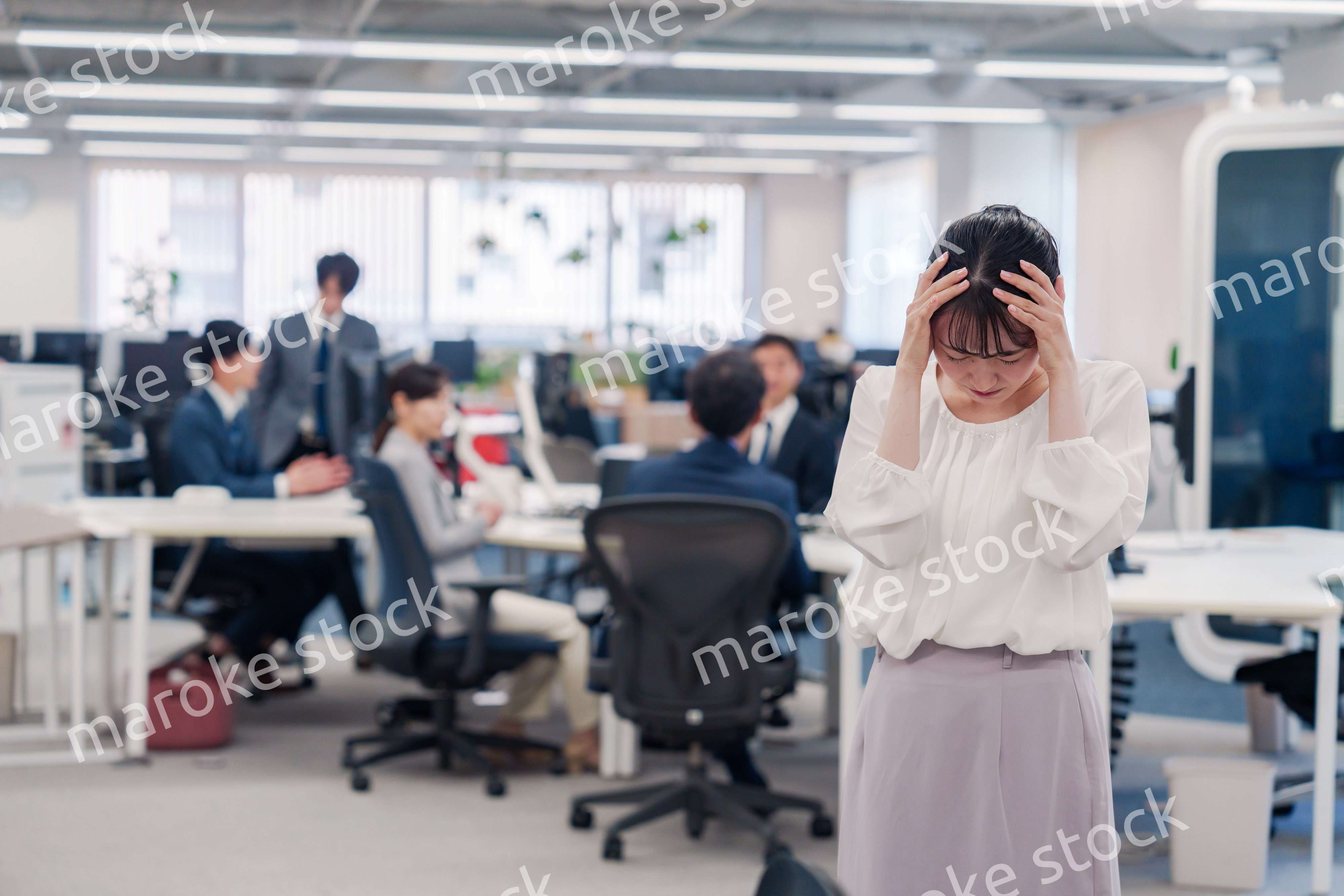 オフィスで頭を抱える女性従業員