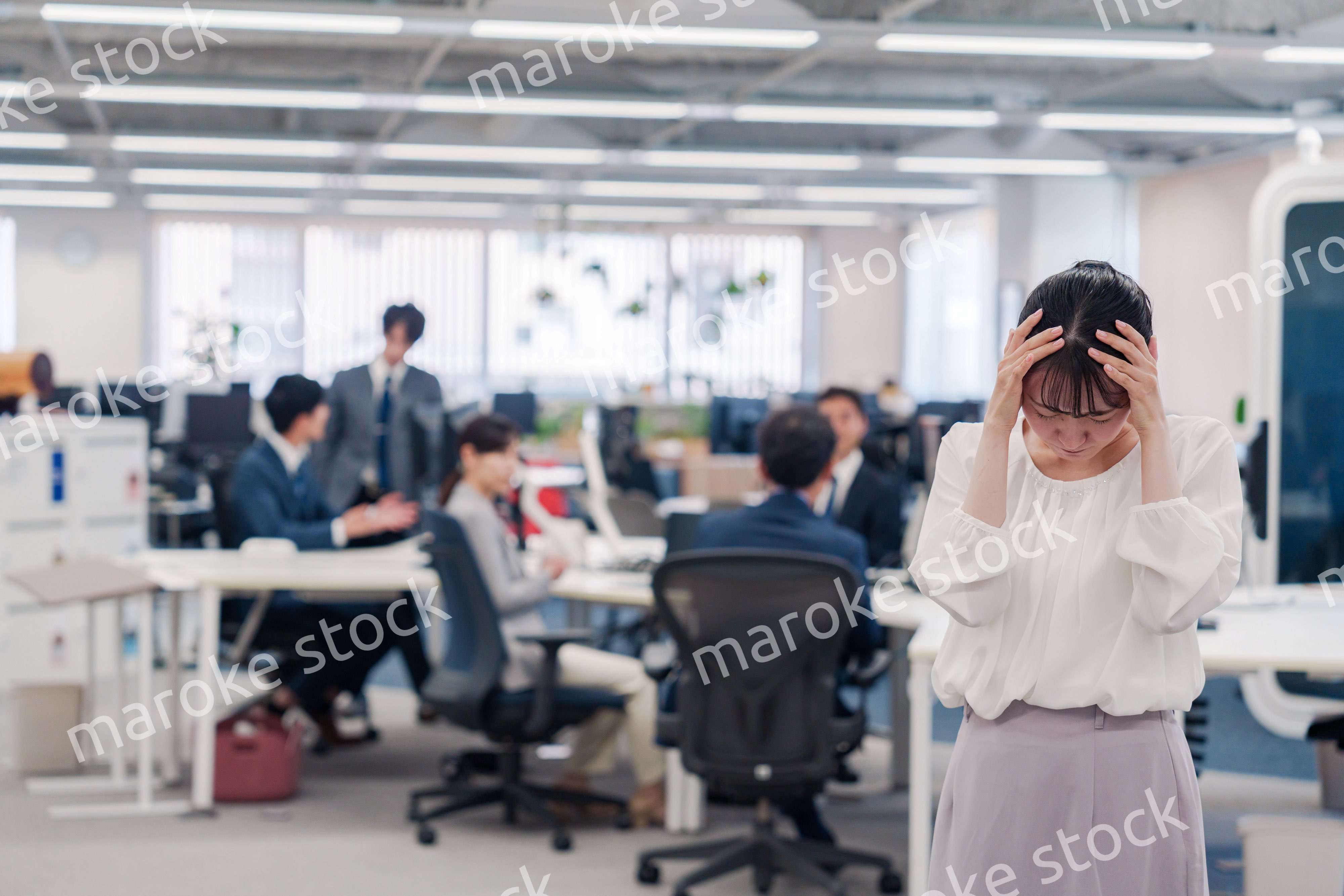 オフィスで頭を抱える女性従業員