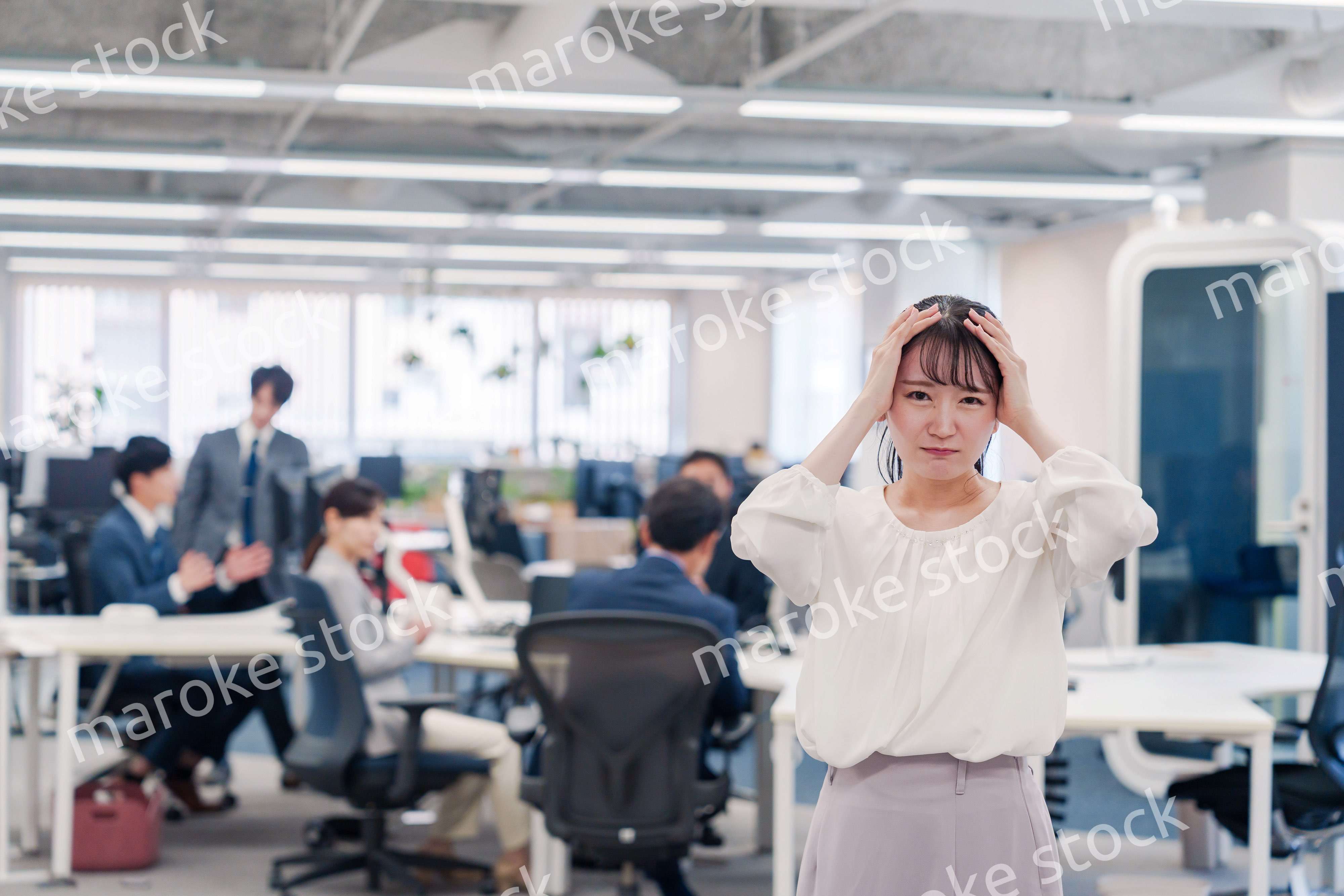オフィスで頭を抱える女性従業員