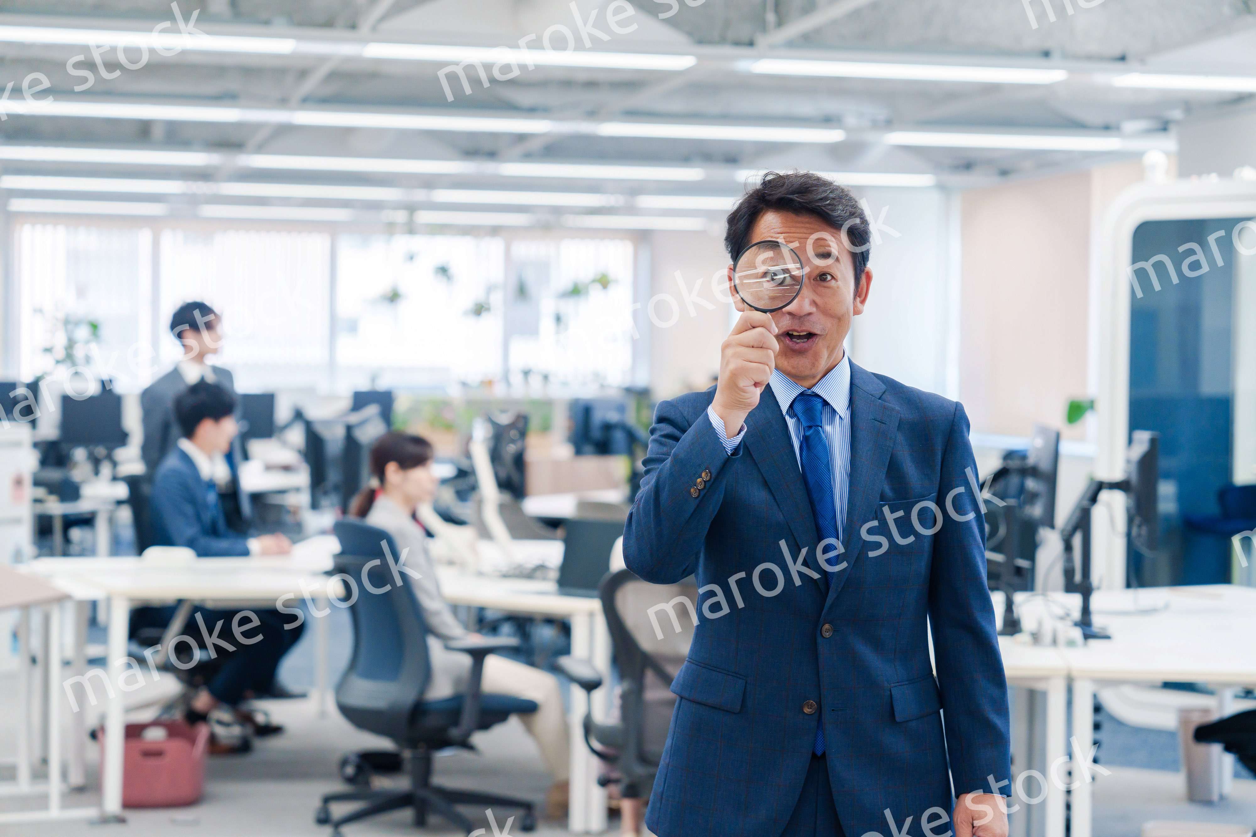 オフィスで虫眼鏡を使う中年のビジネスマン