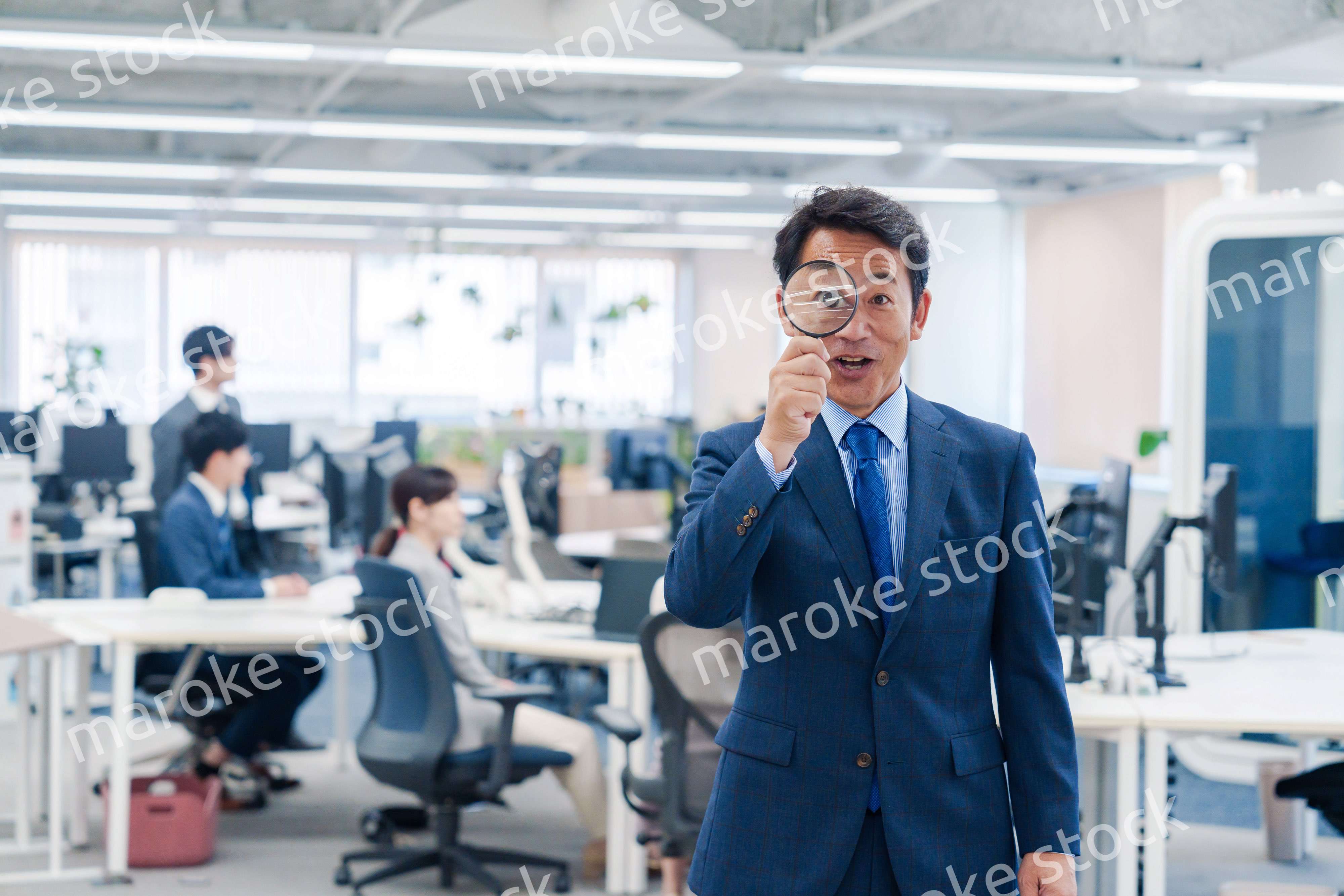 オフィスで虫眼鏡を使う中年のビジネスマン